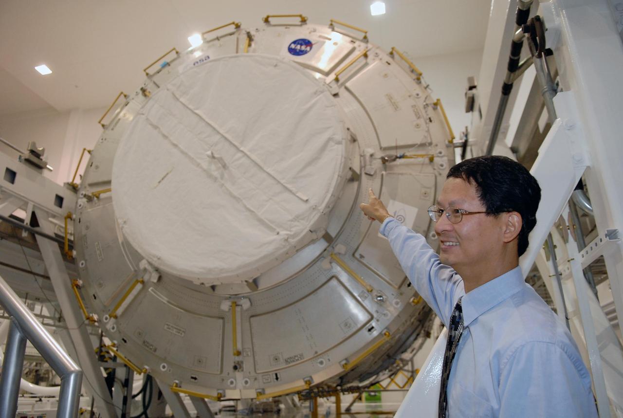 KENNEDY SPACE CENTER, FLA. -- A media event at NASA's Kennedy Space Center highlighted the next piece to be added to the International Space Station, the Italian-built Node-2 module, known as Harmony. At left, Glenn C. Chin, mission manager for International Space Station and Spacecraft Processing, talks to reporters about processing of the Harmony module to which he is pointing. Harmony will launch aboard space shuttle Discovery on mission STS-120, targeted for launch Oct. 23. The module is scheduled to be transferred at the end of the month to Launch Pad 39A, in preparation for its journey to the station. Harmony is approximately 21 feet long and 14 feet in diameter. It will act as an internal connecting port and passageway to additional international science labs and cargo spacecraft. The pressurized module will increase the living and working space inside the station and serve as a work platform outside for the station's robotic arm. Photo credit: NASA/Kim Shiflett