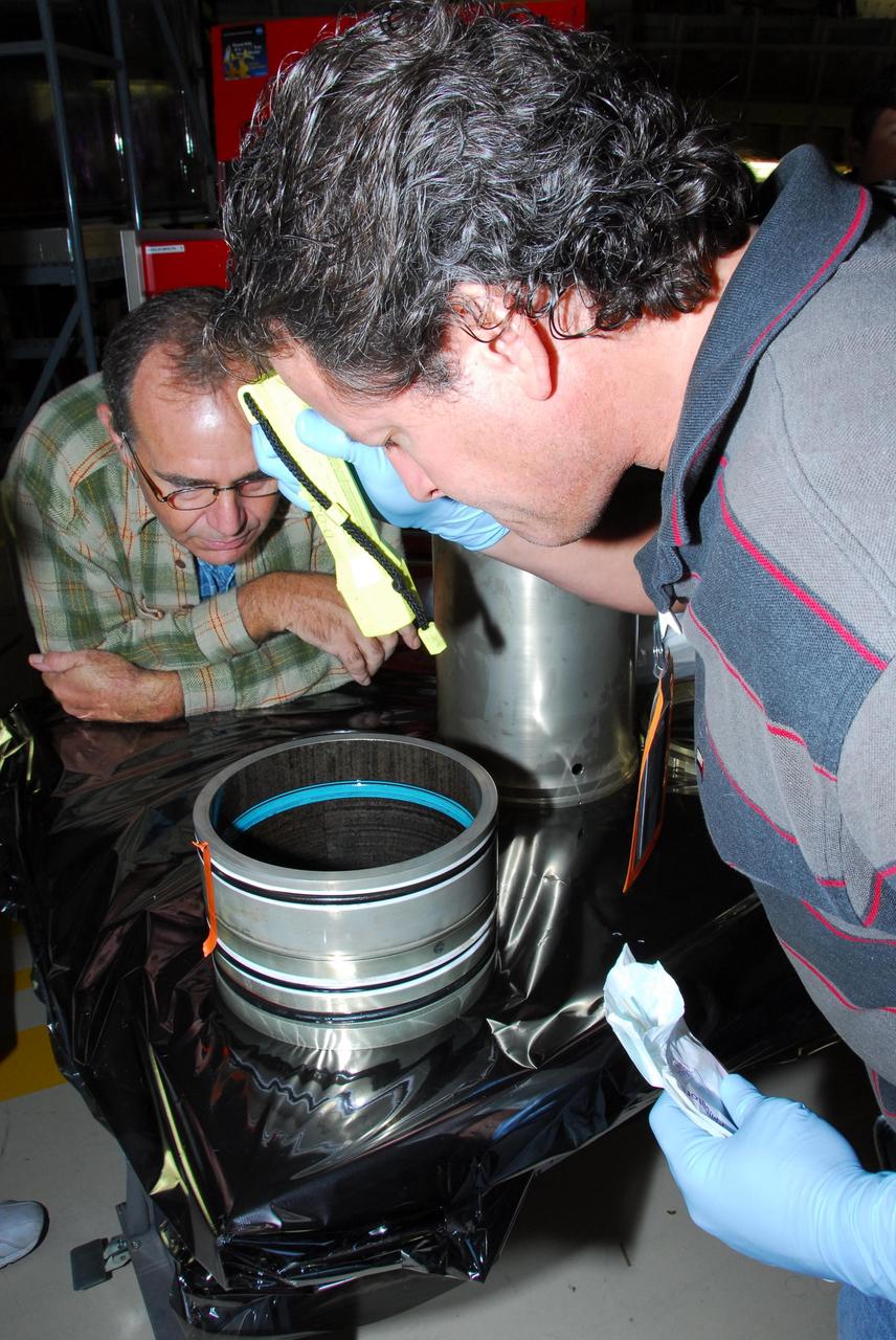 KENNEDY SPACE CENTER, FLA. -- In Orbiter Processing Facility bay 3, United Space Alliance and B.F. Goodrich technicians look inside part of space shuttle Discovery's right main-gear strut where a leaking seal has been found. The struts act as shock absorbers during the shuttle's landing. The seal will be replaced.  Engineers determined the observed leak of hydraulic fluid in the main landing gear strut exceeded specification and could not be reduced to an acceptable rate. Removing the strut and replacing seals require disconnecting and replacing the brakes and tires, disconnecting and reconnecting instruments and other requirements to allow access to the strut.  Discovery had been scheduled to roll over Sept. 19 from its processing hangar to the Vehicle Assembly Building. A new rollover date will be set after technicians determine how long replacing the seal will take.  Photo credit: NASA/George Shelton