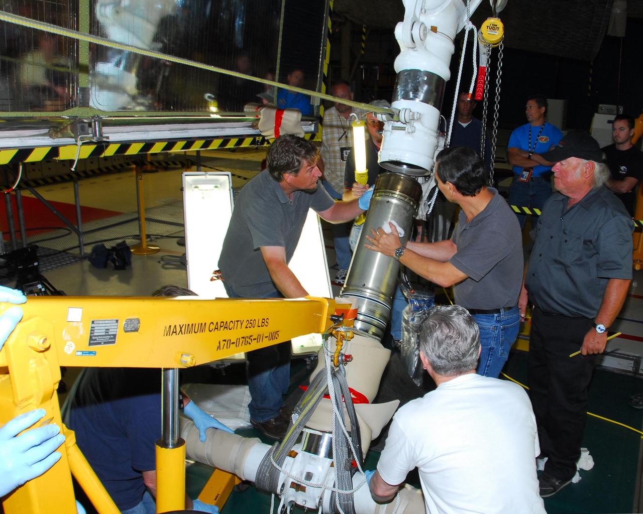 KENNEDY SPACE CENTER, FLA. --In bay 3 of the Orbiter Processing Facility, United Space Alliance technicians reassemble space shuttle Discovery's right main-gear strut back together.  The components were removed in order to replace a hydraulic seal inside.  Engineers determined an observed leak of hydraulic fluid in the main landing gear strut exceeded specification and could not be reduced to an acceptable rate. Thus, the leaky seal and three other seals were replaced.  Prior to discovery of the leak, the vehicle had been scheduled to roll over Sept. 19 from the OPF to the Vehicle Assembly Building. A new rollover date will be set for Discovery, which is targeted for launch on Oct. 23.  Photo credit: NASA/George Shelton
