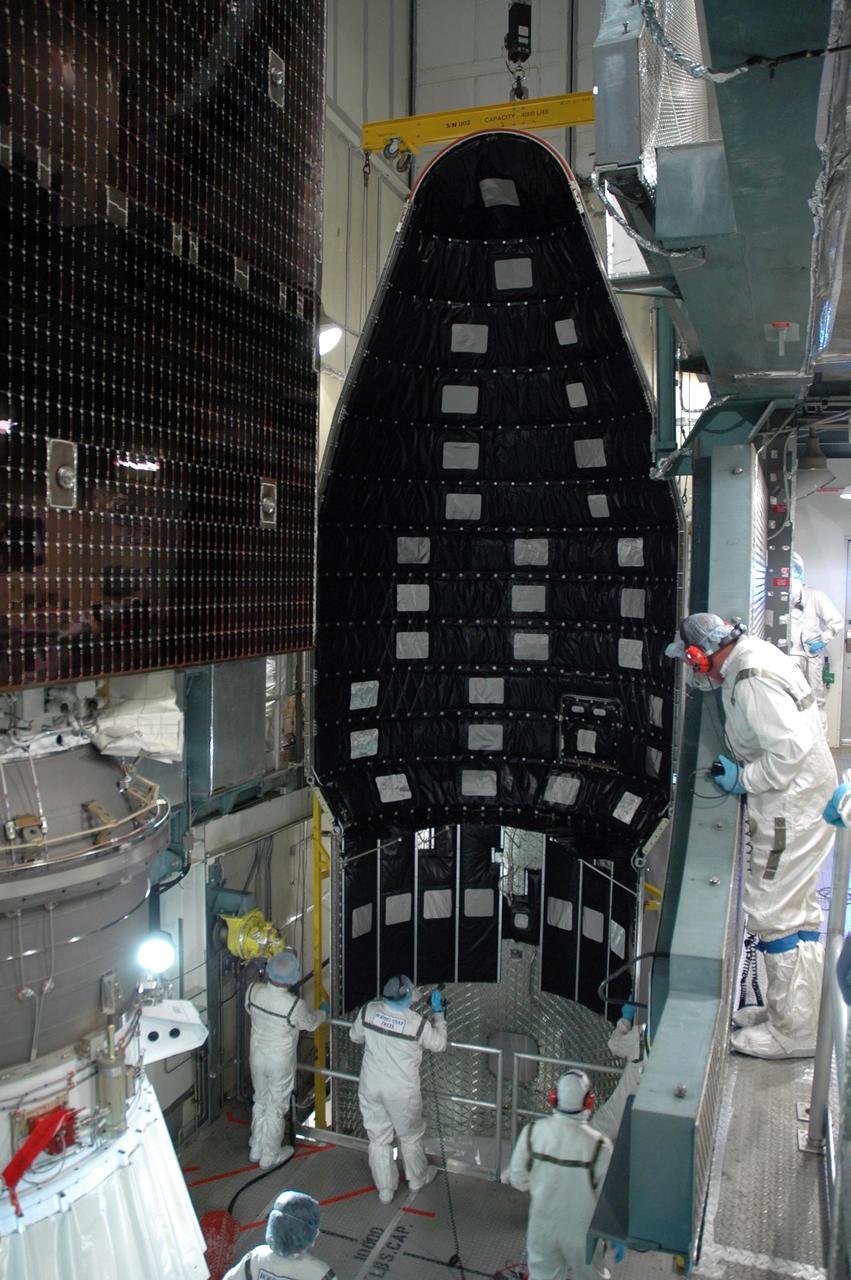 KENNEDY SPACE CENTER, FLA. --   Inside the mobile service tower on Launch Pad 17-B at Cape Canaveral Air Force Station, the first half of the fairing is being moved into place for installation around the Dawn spacecraft.  The fairing is a molded structure that fits flush with the outside surface of the Delta II upper stage booster and forms an aerodynamically smooth nose cone, protecting the spacecraft during launch and ascent.   Dawn is scheduled to launch between 7:25 and 7:54 a.m. on Sept. 26 aboard a Delta II rocket.  Photo credit: NASA/Jim Grossmann
