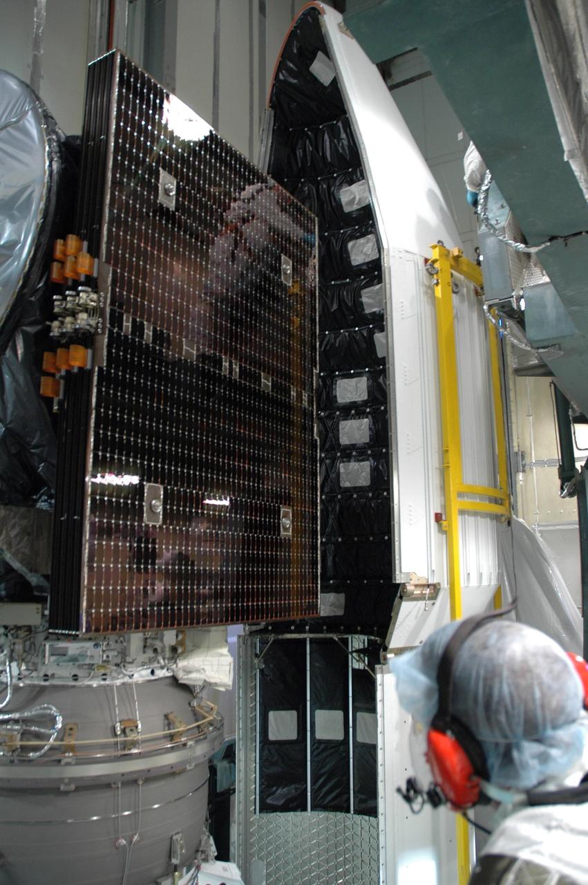KENNEDY SPACE CENTER, FLA. --   Inside the mobile service tower on Launch Pad 17-B at Cape Canaveral Air Force Station, the first half of the fairing is moved closer to the Dawn spacecraft for installation.  The fairing is a molded structure that fits flush with the outside surface of the Delta II upper stage booster and forms an aerodynamically smooth nose cone, protecting the spacecraft during launch and ascent.   Dawn is scheduled to launch between 7:25 and 7:54 a.m. on Sept. 26 aboard a Delta II rocket.  Photo credit: NASA/Jim Grossmann