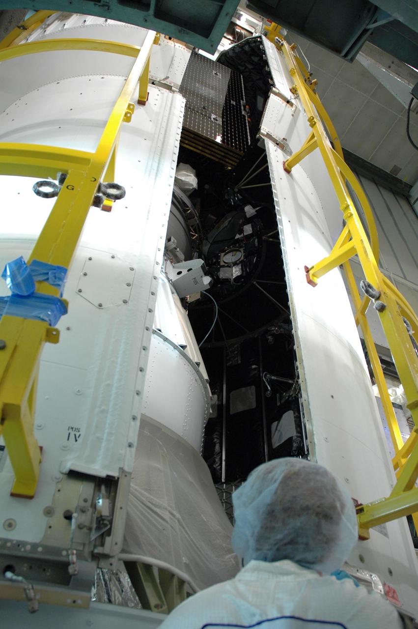 KENNEDY SPACE CENTER, FLA. -- Inside the mobile service tower on Launch Pad 17-B at Cape Canaveral Air Force Station, the second half of the fairing (at right) is moved closer to the first half for installation around the Dawn spacecraft, glimpsed inside.  The first half is already in place.The fairing is a molded structure that fits flush with the outside surface of the Delta II upper stage booster and forms an aerodynamically smooth nose cone, protecting the spacecraft during launch and ascent.   Dawn is scheduled to launch between 7:25 and 7:54 a.m. on Sept. 26 aboard a Delta II rocket.  Photo credit: NASA/Jim Grossmann
