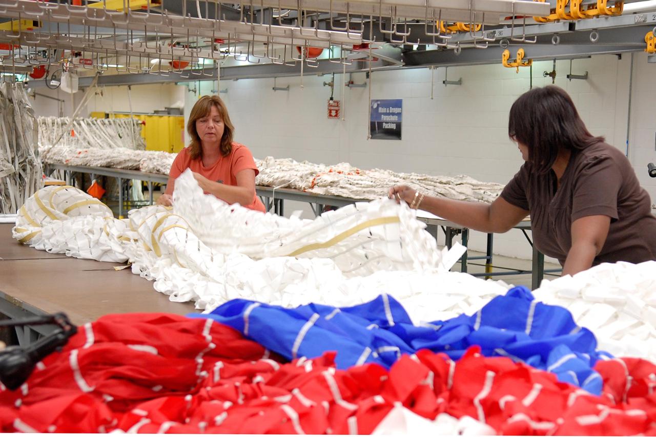 KENNEDY SPACE CENTER, FLA. -- Workers prepare a parachute for an upcoming test at the Parachute Refurbishment Facility. The first stage of the new Ares I rocket and Orion spacecraft will use parachutes to return to Earth.  Current tests are being performed in Arizona to make sure the designs can safely handle their intended weight.  Ares I is an in-line, two-stage rocket that will transport the Orion crew exploration vehicle to low-Earth orbit. The Ares I first stage will be a five-segment solid rocket booster based on the four-segment design used for the shuttle. As with the shuttle, this booster will fall away when spent, lowered by parachute into the Atlantic Ocean where it can be retrieved for re-use. Unlike the shuttle, the booster will be flying faster, at Mach 6, when its separation from the rest of Ares I occurs.  Photo credit: NASA/Kim Shiflett