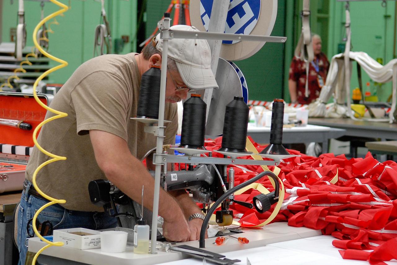 KENNEDY SPACE CENTER, FLA. -- A worker sews a parachute being prepared for an upcoming test at the Parachute Refurbishment Facility. The first stage of the new Ares I rocket and Orion spacecraft will use parachutes to return to Earth.  Current tests are being performed in Arizona to make sure the designs can safely handle their intended weight.  Ares I is an in-line, two-stage rocket that will transport the Orion crew exploration vehicle to low-Earth orbit. The Ares I first stage will be a five-segment solid rocket booster based on the four-segment design used for the shuttle. As with the shuttle, this booster will fall away when spent, lowered by parachute into the Atlantic Ocean where it can be retrieved for re-use. Unlike the shuttle, the booster will be flying faster, at Mach 6, when its separation from the rest of Ares I occurs.  Photo credit: NASA/Kim Shiflett