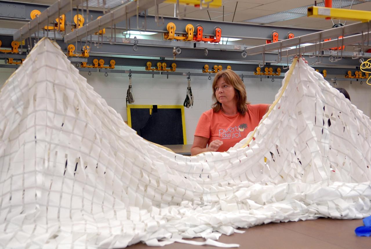 KENNEDY SPACE CENTER, FLA. --  A worker prepares a parachute for an upcoming test at the Parachute Refurbishment Facility. The first stage of the new Ares I rocket and Orion spacecraft will use parachutes to return to Earth.  Current tests are being performed in Arizona to make sure the designs can safely handle their intended weight.  Ares I is an in-line, two-stage rocket that will transport the Orion crew exploration vehicle to low-Earth orbit. The Ares I first stage will be a five-segment solid rocket booster based on the four-segment design used for the shuttle. As with the shuttle, this booster will fall away when spent, lowered by parachute into the Atlantic Ocean where it can be retrieved for re-use. Unlike the shuttle, the booster will be flying faster, at Mach 6, when its separation from the rest of Ares I occurs.  Photo credit: NASA/Kim Shiflett