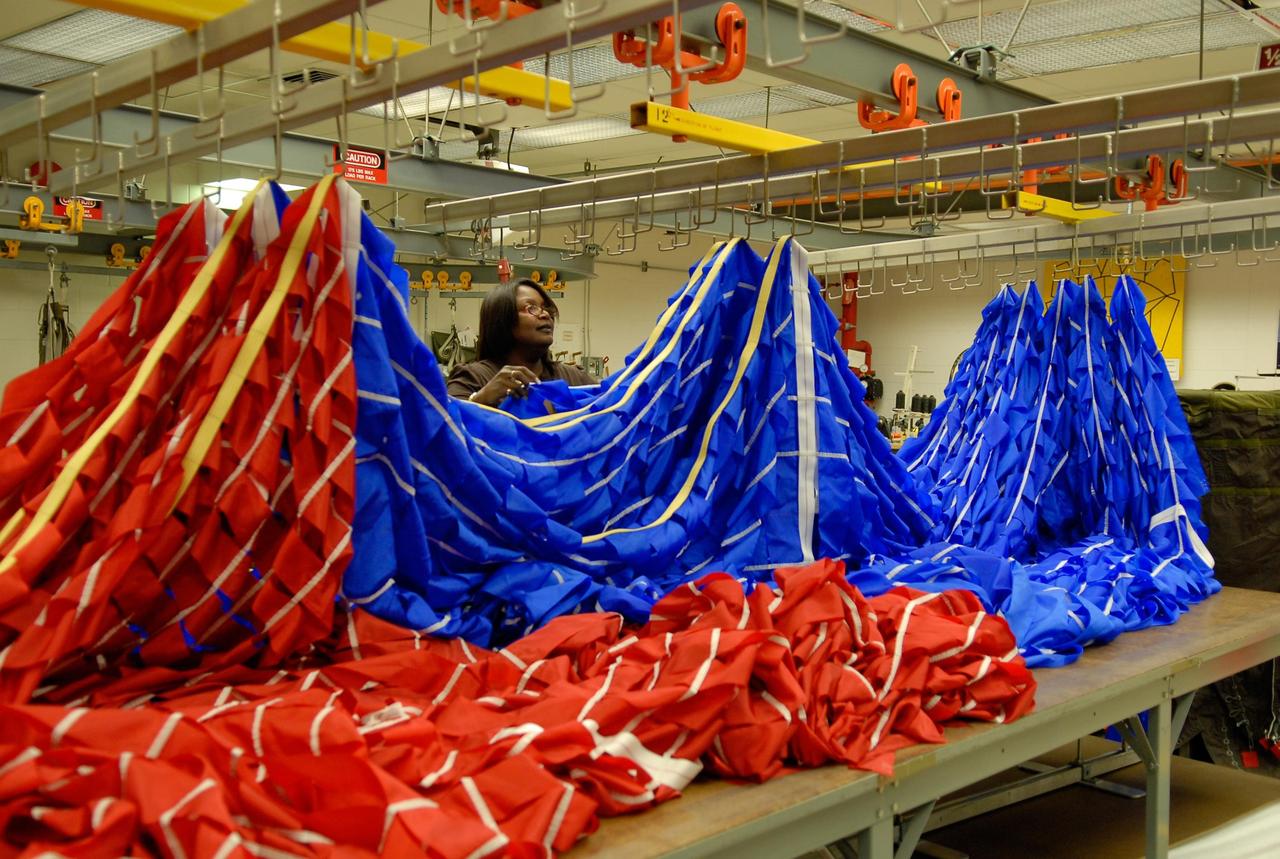 KENNEDY SPACE CENTER, FLA. -- A worker hangs portions of a parachute in preparation for an upcoming test at the Parachute Refurbishment Facility. The first stage of the new Ares I rocket and Orion spacecraft will use parachutes to return to Earth. Current tests are being performed in Arizona to make sure the designs can safely handle their intended weight. Ares I is an in-line, two-stage rocket that will transport the Orion crew exploration vehicle to low-Earth orbit. The Ares I first stage will be a five-segment solid rocket booster based on the four-segment design used for the shuttle. As with the shuttle, this booster will fall away when spent, lowered by parachute into the Atlantic Ocean where it can be retrieved for re-use. Unlike the shuttle, the booster will be flying faster, at Mach 6, when its separation from the rest of Ares I occurs. Photo credit: NASA/Kim Shiflett