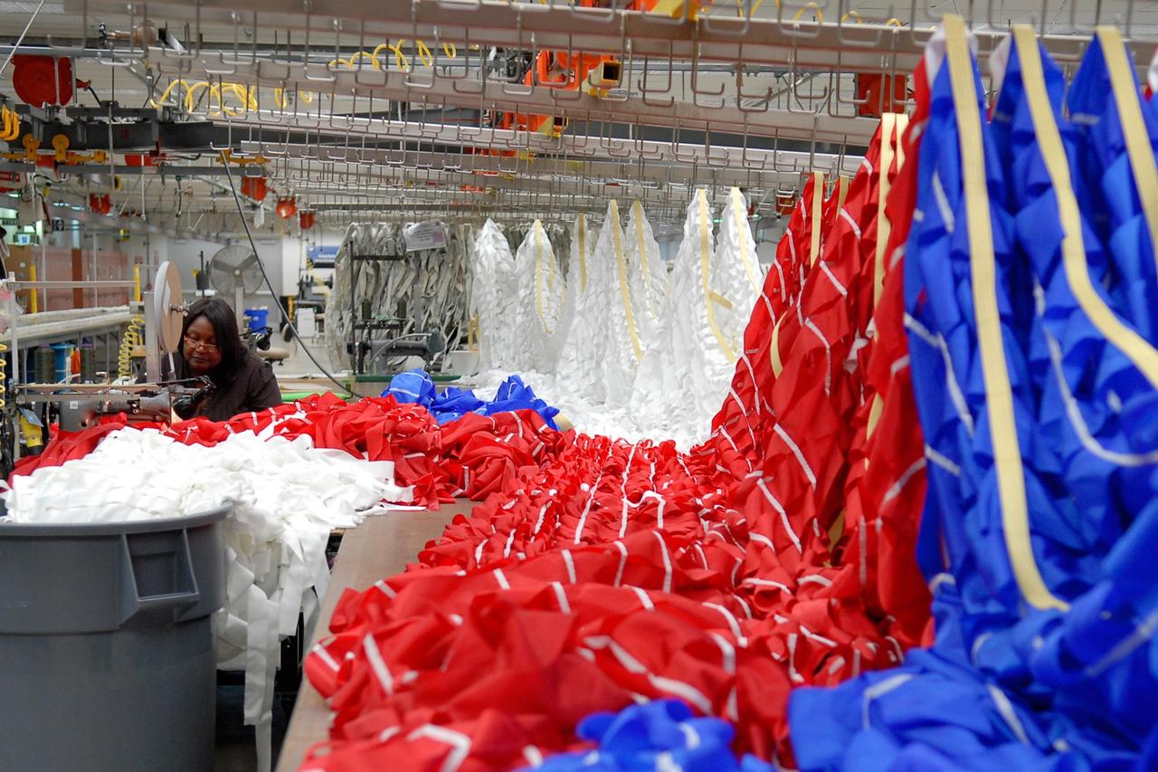 KENNEDY SPACE CENTER, FLA. -- A worker sews a parachute being prepared for an upcoming test at the Parachute Refurbishment Facility. The first stage of the new Ares I rocket and Orion spacecraft will use parachutes to return to Earth. Current tests are being performed in Arizona to make sure the designs can safely handle their intended weight. Ares I is an in-line, two-stage rocket that will transport the Orion crew exploration vehicle to low-Earth orbit. The Ares I first stage will be a five-segment solid rocket booster based on the four-segment design used for the shuttle. As with the shuttle, this booster will fall away when spent, lowered by parachute into the Atlantic Ocean where it can be retrieved for re-use. Unlike the shuttle, the booster will be flying faster, at Mach 6, when its separation from the rest of Ares I occurs. Photo credit: NASA/Kim Shiflett