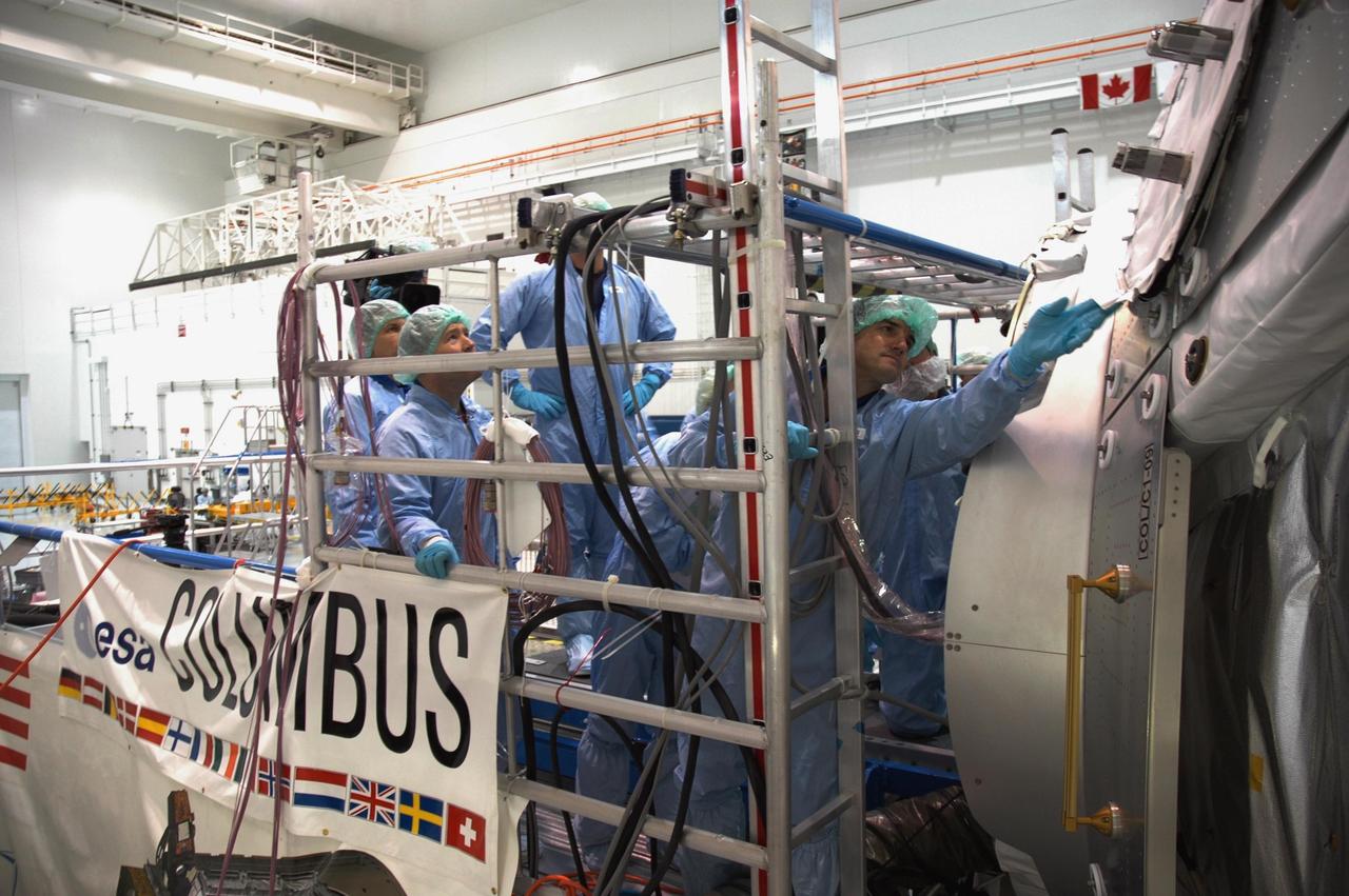 KENNEDY SPACE CENTER, FLA. -- Members of the STS-122 crew look over the Columbus Research Laboratory in the Space Station Processing Facility. The crew is at Kennedy to take part in a crew equipment interface test, which helps familiarize them with equipment and payloads for the mission. Among the activities standard to a CEIT are harness training, inspection of the thermal protection system and camera operation for planned extravehicular activities, or EVAs. The crew comprises Commander Stephen Frick, Pilot Alan Poindexter, and Mission Specialists Rex Walheim, Stanley Love, Leland Melvin and Hans Schlegel, who represents the European Space Agency. The Columbus Lab is Europe’s largest contribution to the construction of the International Space Station. It will support scientific and technological research in a microgravity environment. Columbus, a program of ESA, is a multifunctional, pressurized laboratory that will be permanently attached to Node 2 of the space station to carry out experiments in materials science, fluid physics and biosciences, as well as to perform a number of technological applications. STS-122 is targeted for launch in December. Photo credit: NASA/Jim Grossmann