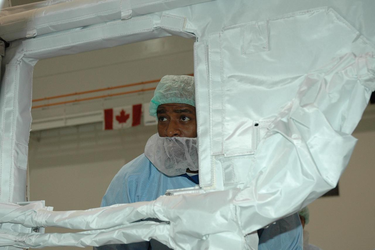 KENNEDY SPACE CENTER, FLA. -- STS-122 Mission Specialist Leland Melvin gets a close look at the Columbus Research Laboratory in the Space Station Processing Facility. The crew is at Kennedy to take part in a crew equipment interface test, which helps familiarize them with equipment and payloads for the mission. Among the activities standard to a CEIT are harness training, inspection of the thermal protection system and camera operation for planned extravehicular activities, or EVAs. The crew comprises Commander Stephen Frick, Pilot Alan Poindexter, and Mission Specialists Rex Walheim, Stanley Love, Leland Melvin and Hans Schlegel, who represents the European Space Agency. The Columbus Lab is Europe’s largest contribution to the construction of the International Space Station. It will support scientific and technological research in a microgravity environment. Columbus, a program of ESA, is a multifunctional, pressurized laboratory that will be permanently attached to Node 2 of the space station to carry out experiments in materials science, fluid physics and biosciences, as well as to perform a number of technological applications. STS-122 is targeted for launch in December. Photo credit: NASA/Jim Grossmann