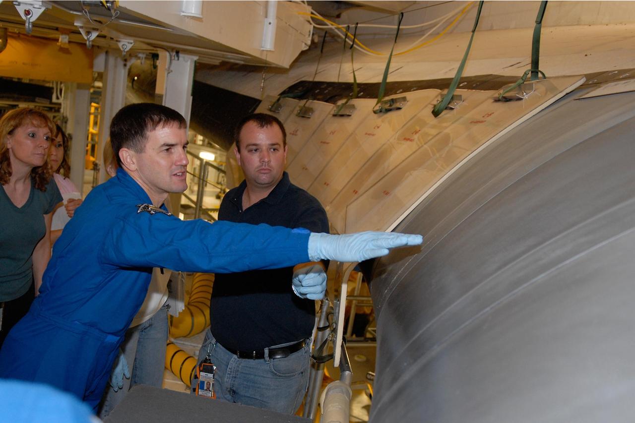 KENNEDY SPACE CENTER, FLA. -- In the Orbiter Processing Facility, STS-122 Mission Specialist Rex Walheim reaches toward the wing of space shuttle Atlantis.  The crew is at Kennedy to take part in a crew equipment interface test, or CEIT, which helps familiarize them with equipment and payloads for the mission.  Among the activities standard to a CEIT are harness training, inspection of the thermal protection system and camera operation for planned extravehicular activities, or EVAs.  STS-122 is targeted for launch in December.   Photo credit: NASA/Kim Shiflett