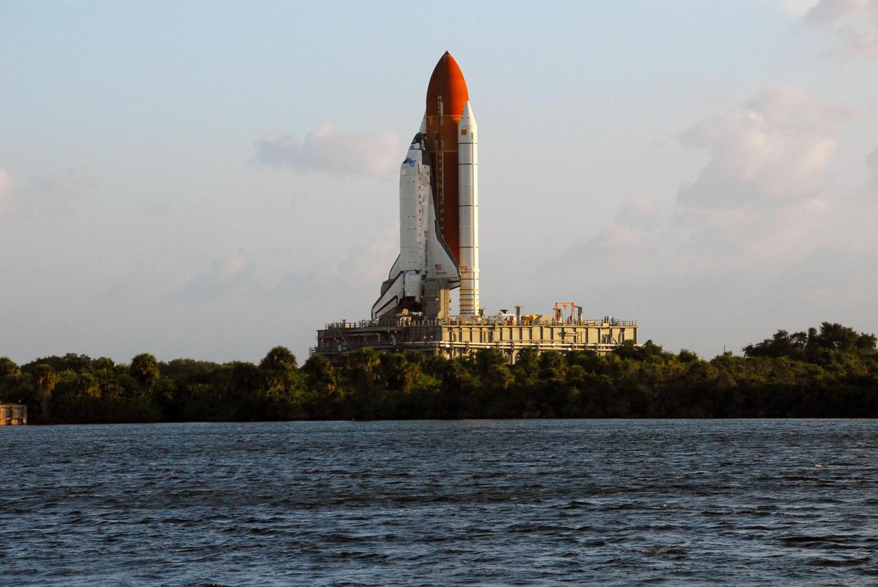 KENNEDY SPACE CENTER, FLA. -- Space Shuttle Discovery, atop a mobile launch platform, passes by the turn basin in Launch Complex 39 toward Pad A as the sun rises on a balmy Florida morning. First motion out of the VAB was at 6:47 a.m. EDT. Rollout is a milestone for Discovery's launch to the International Space Station on mission STS-120, targeted for Oct. 23. The crew will be delivering and installing the Italian-built U.S. Node 2, named Harmony. The pressurized module will act as an internal connecting port and passageway to additional international science labs and cargo spacecraft. In addition to increasing the living and working space inside the station, it also will serve as a work platform outside for the station's robotic arm.   Photo credit: NASA/George Shelton