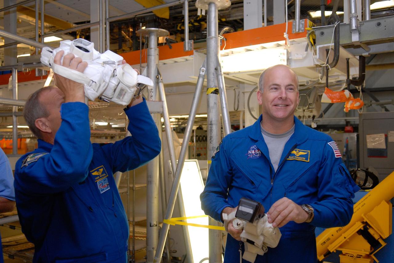 KENNEDY SPACE CENTER, FLA. --  In the Orbiter Processing Facility, members of the STS-122 crew practice handling cameras that will be used during the mission.  At left is Mission Specialist Hans Schlegel.  At right is Pilot Alan Poindexter.  Schlegel represents the European Space Agency.  The crew is at Kennedy Space Center to take part in a crew equipment interface test, which helps familiarize them with equipment and payloads for the mission.  Among the activities standard to a CEIT are harness training, inspection of the thermal protection system and camera operation for planned extravehicular activities, or EVAs.  The mission will carry and install the Columbus Lab,  a multifunctional, pressurized laboratory that will be permanently attached to Node 2 of the space station to carry out experiments in materials science, fluid physics and biosciences, as well as to perform a number of technological applications. It is Europe’s largest contribution to the construction of the International Space Station and will support scientific and technological research in a microgravity environment.  STS-122 is targeted for launch in December.   Photo credit: NASA/Kim Shiflett
