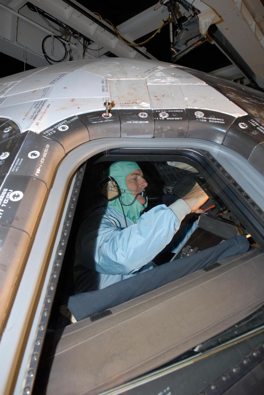 KENNEDY SPACE CENTER, FLA. -- In the Orbiter Processing Facility, STS-122 Pilot Alan Poindexter checks out the cockpit on space shuttle Atlantis. The crew is at Kennedy Space Center to take part in a crew equipment interface test, which helps familiarize them with equipment and payloads for the mission.  Among the activities standard to a CEIT are harness training, inspection of the thermal protection system and camera operation for planned extravehicular activities, or EVAs.  The mission will carry and install the Columbus Lab,  a multifunctional, pressurized laboratory that will be permanently attached to Node 2 of the space station to carry out experiments in materials science, fluid physics and biosciences, as well as to perform a number of technological applications. It is Europe’s largest contribution to the construction of the International Space Station and will support scientific and technological research in a microgravity environment.  STS-122 is targeted for launch in December.   Photo credit: NASA/Kim Shiflett