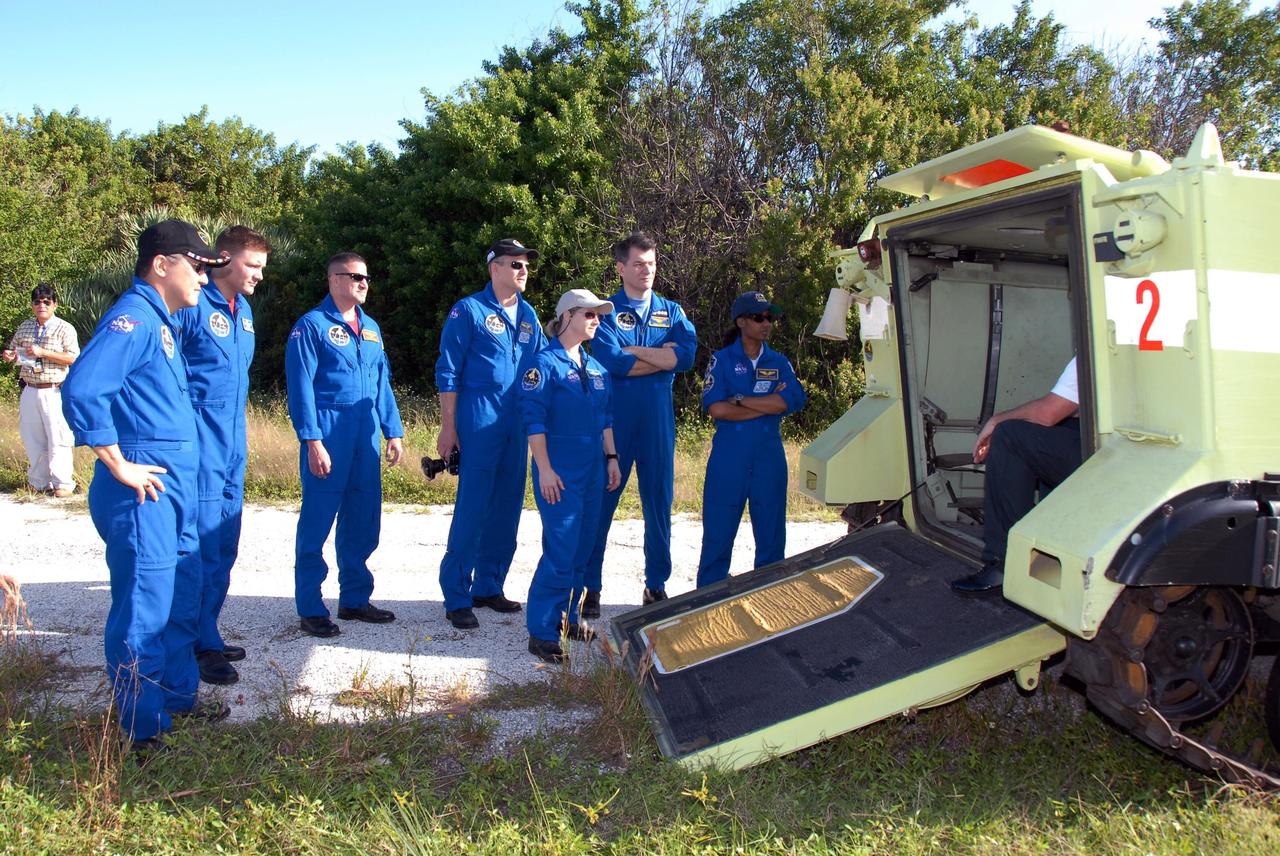 KENNEDY SPACE CENTER, FLA. --  Outside the M-113 armored personnel carrier,  STS-120 crew members listen to instructions on its use for emergency exit procedures from Launch Pad 39A.   From left are Mission Specialists Daniel Tani and Doug Wheelock, Pilot George Zamka, Mission Specialist Scott Parazynski, Commander Pamela Melroy, and Mission Specialists Paolo Nespoli and Stephanie Wilson.  Nespoli represents the European Space Agency. The training is part of terminal countdown demonstration test, or TCDT, activities the crew is undertaking at NASA's Kennedy Space Center. The TCDT also includes equipment familiarization and a simulated launch countdown. Mission STS-120, which will carry the Italian-built U.S. Node 2 to the International Space Station, is targeted for launch on Oct. 23.  Photo credit: NASA/Kim Shiflett
