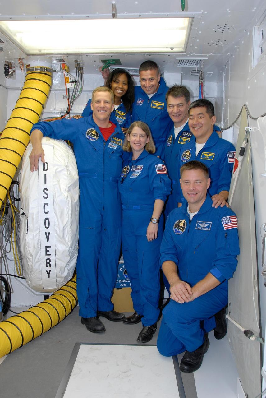 KENNEDY SPACE CENTER, FLA. -- Gathered in the white room on Launch Pad 39A, alongside space shuttle Discovery, the STS-120 crew pauses for a photo. Clockwise from the bottom are Commander Pamela Melroy, Mission Specialists Scott Parazynski and Stephanie Wilson, Pilot George Zamka, Mission Specialists Paolo Nespoli, Daniel Tani and Doug Wheelock (kneeling). Nespoli represents the European Space Agency. After the mission, Tani will remain aboard the International Space Station and return with the STS-122 crew, targeted to launch Dec. 6. The crew is at NASA's Kennedy Space Center for the pre-launch terminal countdown demonstration test, or TCDT. The TCDT provides astronauts and ground crews an opportunity to participate in various simulated countdown activities, including equipment familiarization and emergency training. The STS-120 mission will deliver the U.S. Node 2 module, named Harmony, aboard space shuttle Discovery to the International Space Station. Launch of Discovery on mission STS-120 is targeted for Oct. 23 at 11:38 a.m. EDT on a 14-day mission. Photo credit: NASA/Kim Shiflett