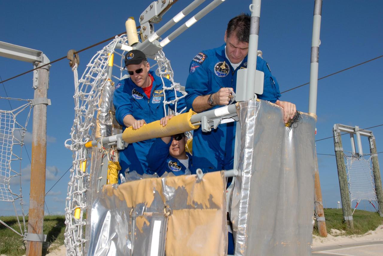 KENNEDY SPACE CENTER, FLA. -- The STS-120 crew is at NASA's Kennedy Space Center for the pre-launch terminal countdown demonstration test, or TCDT.  Practicing to get out of the slidewire basket at the landing site during emergency egress training are Mission Specialists Scott Parazynski, Daniel Tani and Paolo Nespoli, who represents the European Space Agency.  After the mission, Tani will remain aboard the International Space Station and return with the STS-122 crew, targeted to launch Dec. 6.  The TCDT provides astronauts and ground crews an opportunity to participate in various simulated countdown activities, including equipment familiarization and emergency training. The STS-120 mission will deliver the U.S. Node 2 module, named Harmony, aboard space shuttle Discovery to the International Space Station.  Launch of Discovery on mission STS-120 is targeted for Oct. 23 at 11:38 a.m. EDT on a 14-day mission.  Photo credit: NASA/Kim Shiflett