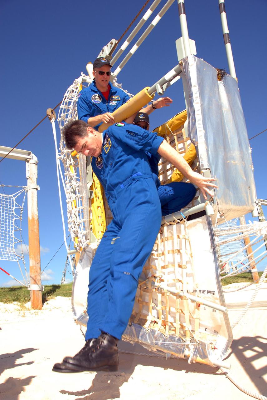 KENNEDY SPACE CENTER, FLA. -- During emergency egress training as part of the pre-launch terminal countdown demonstration test, or TCDT, STS-120 crew members practice getting out of the slidewire basket at the landing site. Jumping out of the basket is Mission Specialist Paolo Nespoli, who represents the European Space Agency; behind him are Mission Specialists Scott Parazynski and Daniel Tani. After the mission, Tani will remain aboard the International Space Station and return with the STS-122 crew, targeted to launch Dec. 6. The TCDT provides astronauts and ground crews an opportunity to participate in various simulated countdown activities, including equipment familiarization and emergency training. The STS-120 mission will deliver the U.S. Node 2 module, named Harmony, aboard space shuttle Discovery to the International Space Station. Launch of Discovery on mission STS-120 is targeted for Oct. 23 at 11:38 a.m. EDT on a 14-day mission. Photo credit: NASA/Kim Shiflett