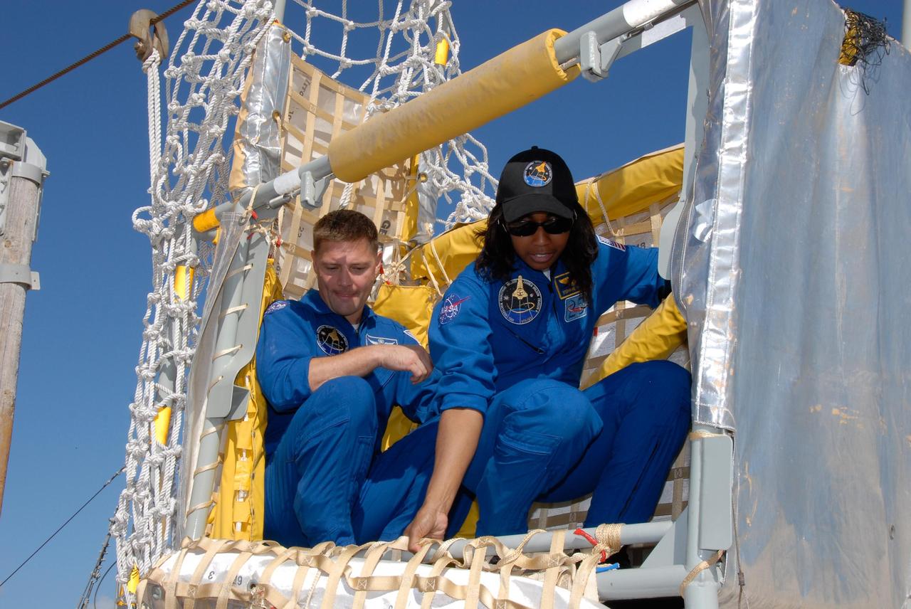 KENNEDY SPACE CENTER, FLA. -- During emergency egress training as part of the pre-launch terminal countdown demonstration test, or TCDT, STS-120 crew members learn how to get out of the slidewire basket at the landing site. In the basket are Mission Specialists Doug Wheelock and Stephanie Wilson. The TCDT provides astronauts and ground crews an opportunity to participate in various simulated countdown activities, including equipment familiarization and emergency training. The STS-120 mission will deliver the U.S. Node 2 module, named Harmony, aboard space shuttle Discovery to the International Space Station. Launch of Discovery on mission STS-120 is targeted for Oct. 23 at 11:38 a.m. EDT on a 14-day mission. Photo credit: NASA/Kim Shiflett
