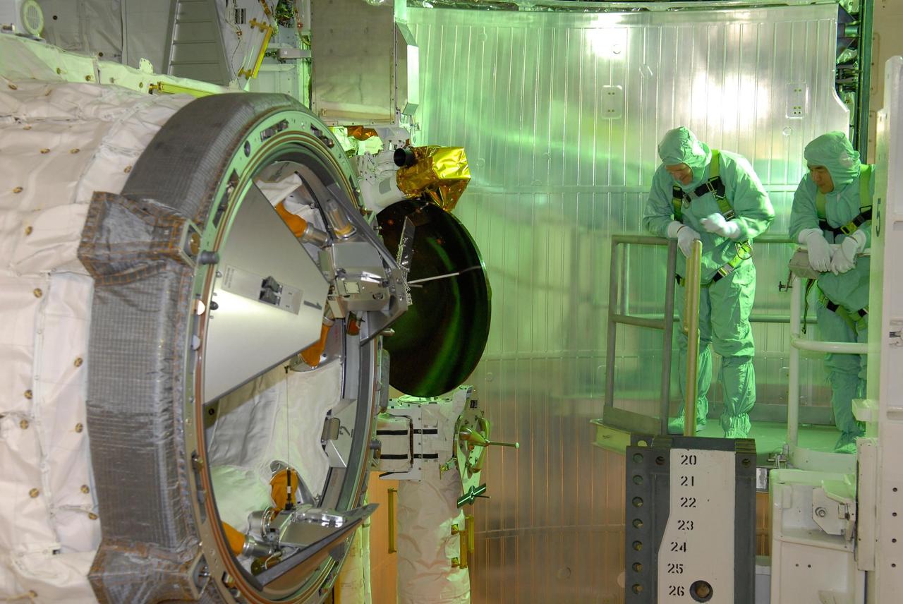 KENNEDY SPACE CENTER, FLA. --  In space shuttle Discovery's payload bay, STS-120 crew members get a close look at the orbital docking system.  Seen here are Mission Specialists Scott Parazynski (left) and Daniel Tani.  After the mission, Tani will remain aboard the International Space Station and return with the STS-122 crew, targeted to launch Dec. 6.  The TCDT provides astronauts and ground crews an opportunity to participate in various simulated countdown activities, including equipment familiarization and emergency training. The STS-120 mission will deliver the U.S. Node 2 module, named Harmony, aboard space shuttle Discovery to the International Space Station.  Launch of Discovery on mission STS-120 is targeted for Oct. 23 at 11:38 a.m. EDT on a 14-day mission.  Photo credit: NASA/Kim Shiflett