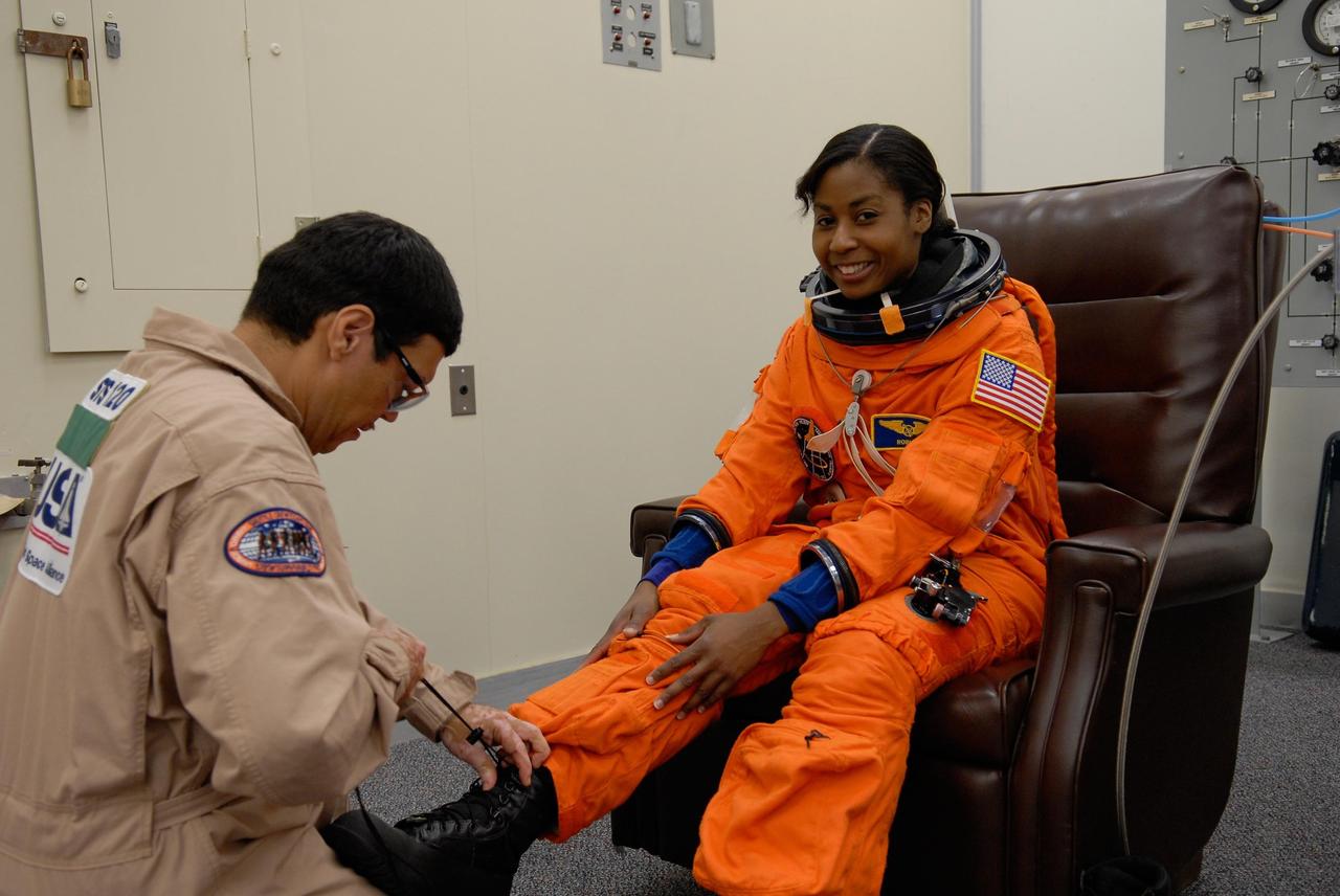 KENNEDY SPACE CENTER, FLA. -- STS-120 Mission Specialist Stephanie Wilson is helped with her boot during suitup for a simulated launch countdown, part of the prelaunch terminal countdown demonstration test, or TCDT. Her name patch reflects the nicknames the crew gave each other for the event. The TCDT provides astronauts and ground crews an opportunity to participate in various launch preparation activities, including equipment familiarization,  emergency training and the simulated countdown. The STS-120 mission will deliver the U.S. Node 2 module, named Harmony, aboard space shuttle Discovery to the International Space Station.  Launch of Discovery on mission STS-120 is targeted for Oct. 23 at 11:38 a.m. EDT on a 14-day mission. Photo credit: NASA/Kim Shiflett
