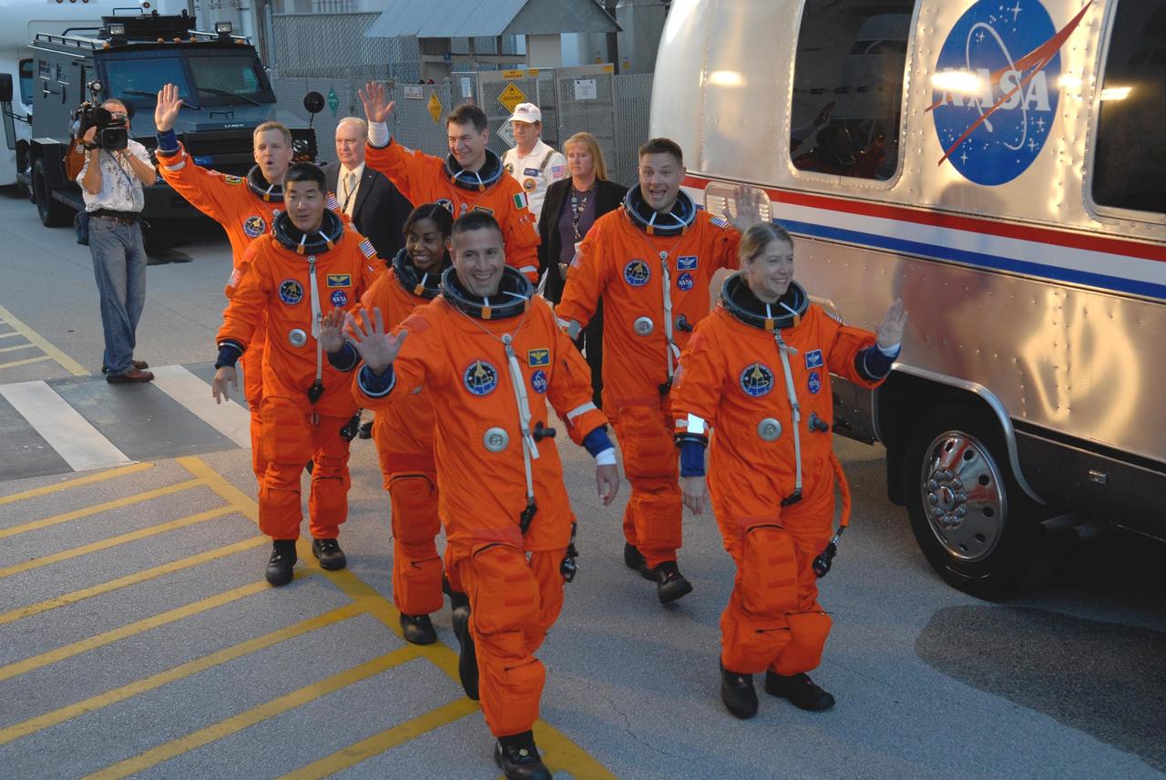 KENNEDY SPACE CENTER, FLA. -- At the Operations and Checkout Building, the crew members of space shuttle mission STS-120 wave to well-wishers as they board the bus that will transport them to Launch Pad 39A during their terminal countdown demonstration test activities. In the left row are, from front, Pilot George Zamka and Mission Specialists Stephanie Wilson, Daniel Tani, and Scott Parazynski. In the right row are, from front, Commander Pam Melroy and Mission Specialists Doug Wheelock and Paolo Nespoli. Nespoli represents the European Space Agency. After the mission, Tani will remain aboard the International Space Station and return with the STS-122 crew, targeted to launch Dec. 6. The terminal countdown demonstration test provides astronauts and ground crews an opportunity to participate in various simulated countdown activities, including equipment familiarization and emergency training. The STS-120 mission will deliver the U.S. Node 2 module, named Harmony, aboard space shuttle Discovery to the ISS. Discovery's launch is targeted for Oct. 23 at 11:38 a.m. EDT on a 14-day mission. Photo credit: NASA/Kim Shiflett