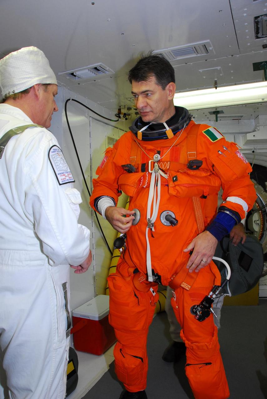 KENNEDY SPACE CENTER, FLA. -- In the white room on Launch Pad 39A, STS-120 Mission Specialist Paolo Nespoli dons a parachute pack before entering space shuttle Discovery for a simulated launch countdown. The countdown is the culmination of the prelaunch terminal countdown demonstration test, or TCDT. The TCDT at NASA's Kennedy Space Center provides astronauts and ground crews an opportunity to participate in various launch preparation activities, including equipment familiarization and emergency training. The STS-120 mission will deliver the U.S. Node 2 module, named Harmony, aboard space shuttle Discovery to the International Space Station. Discovery is targeted to launch on its 14-day mission at 11:38 a.m. EDT on Oct. 23. Photo credit: NASA/George Shelton