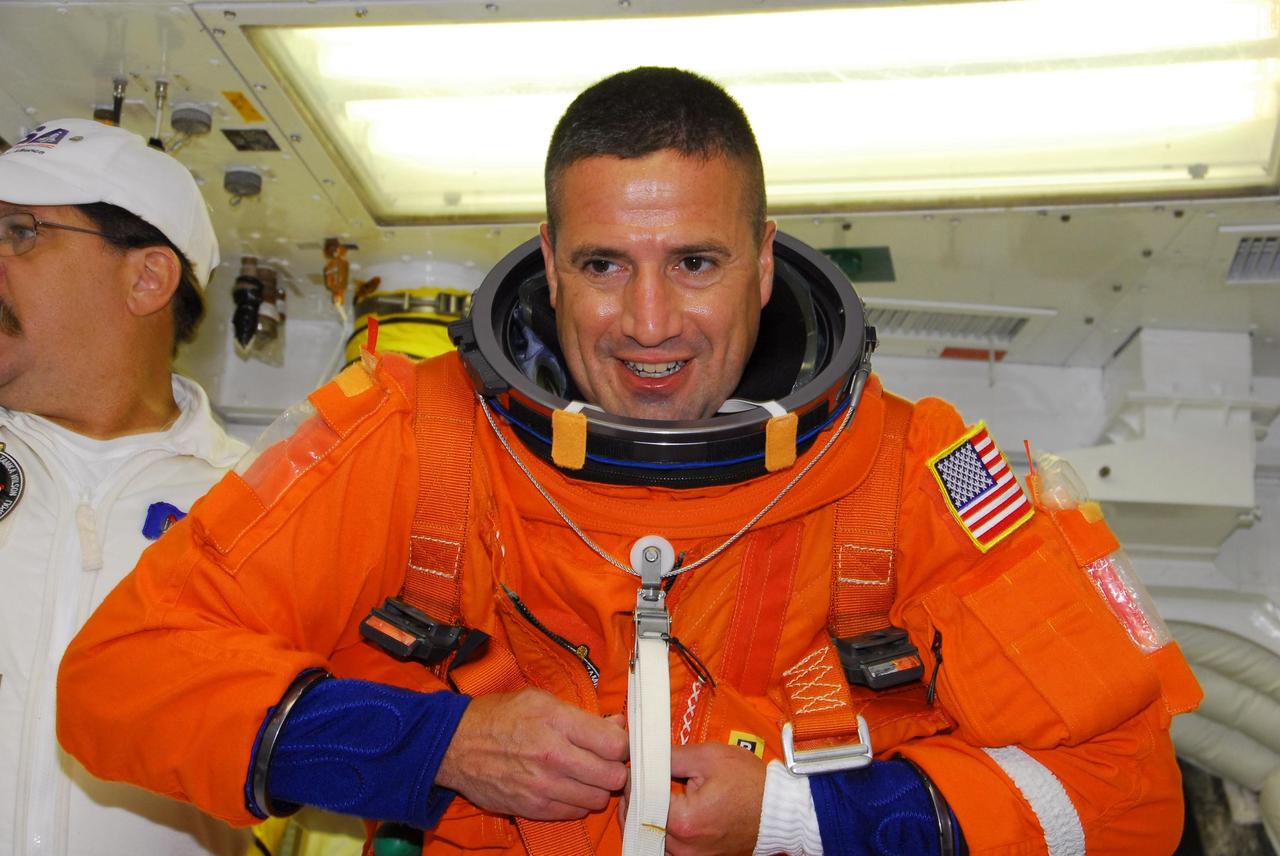 KENNEDY SPACE CENTER, FLA. -- In the white room on Launch Pad 39A, STS-120 Pilot George Zamka finishes getting into his parachute pack before entering space shuttle Discovery for a simulated launch countdown. The countdown is the culmination of the prelaunch terminal countdown demonstration test, or TCDT. The TCDT at NASA's Kennedy Space Center provides astronauts and ground crews an opportunity to participate in various launch preparation activities, including equipment familiarization and emergency training. The STS-120 mission will deliver the U.S. Node 2 module, named Harmony, aboard space shuttle Discovery to the International Space Station. Discovery is targeted to launch on its 14-day mission at 11:38 a.m. EDT on Oct. 23. Photo credit: NASA/George Shelton