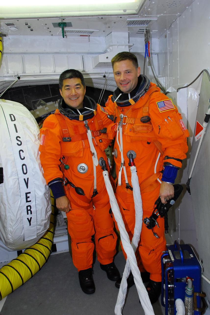 KENNEDY SPACE CENTER, FLA. -- In the white room on Launch Pad 39A, STS-120 Mission Specialists Daniel Tani (left) and Doug Wheelock are ready to enter space shuttle Discovery for a simulated launch countdown. The countdown is the culmination of the prelaunch terminal countdown demonstration test, or TCDT. The TCDT at NASA's Kennedy Space Center provides astronauts and ground crews an opportunity to participate in various launch preparation activities, including equipment familiarization and emergency training. The STS-120 mission will deliver the U.S. Node 2 module, named Harmony, aboard space shuttle Discovery to the International Space Station. Discovery is targeted to launch on its 14-day mission at 11:38 a.m. EDT on Oct. 23. Photo credit: NASA/George Shelton
