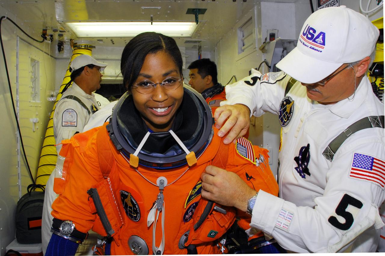 KENNEDY SPACE CENTER, FLA. -- In the white room on Launch Pad 39A, the closeout crew helps STS-120 Mission Specialist Stephanie Wilson with her parachute pack before entering space shuttle Discovery for a simulated launch countdown. The countdown is the culmination of the prelaunch terminal countdown demonstration test, or TCDT. The TCDT at NASA's Kennedy Space Center provides astronauts and ground crews an opportunity to participate in various launch preparation activities, including equipment familiarization and emergency training. The STS-120 mission will deliver the U.S. Node 2 module, named Harmony, aboard space shuttle Discovery to the International Space Station. Discovery is targeted to launch on its 14-day mission at 11:38 a.m. EDT on Oct. 23. Photo credit: NASA/George Shelton