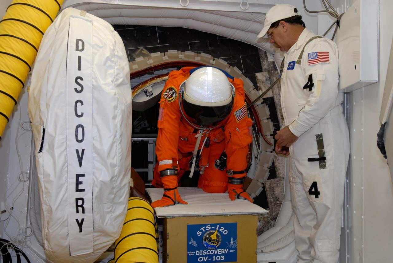 KENNEDY SPACE CENTER, FLA. -- In the white room on Launch Pad 39A, an STS-120 crew member crawls through the hatch after the simulated launch countdown, culmination of the prelaunch terminal countdown demonstration test, or TCDT.  The crew will also practice emergency egress from the pad.  The TCDT at NASA's Kennedy Space Center provides astronauts and ground crews an opportunity to participate in various launch preparation activities, including equipment familiarization and emergency training. The STS-120 mission will deliver the U.S. Node 2 module, named Harmony, aboard space shuttle Discovery to the International Space Station.  Discovery is targeted to launch on its 14-day mission at 11:38 a.m. EDT on Oct. 23. Photo credit: NASA/Kim Shiflett
