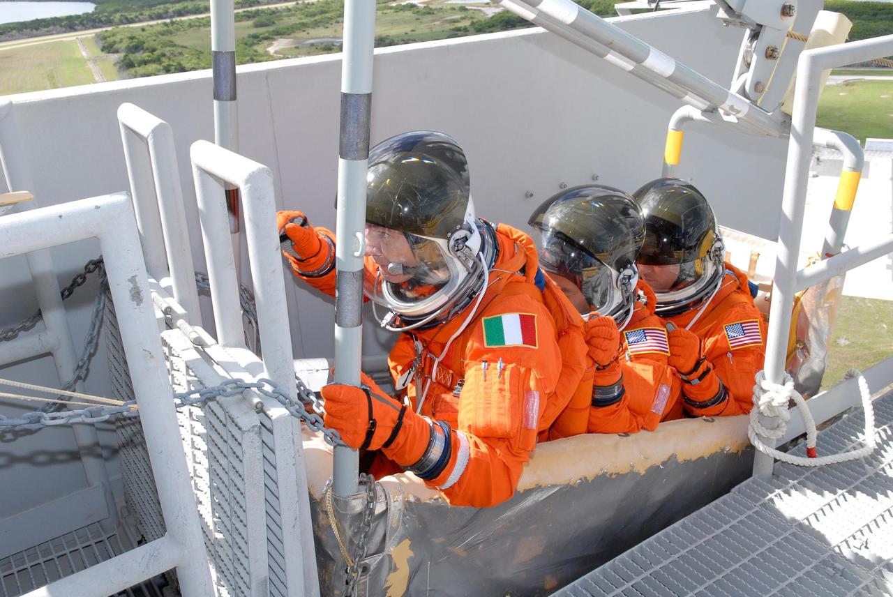 KENNEDY SPACE CENTER, FLA. -- During emergency egress from Launch Pad 39A, STS-120 crew members are in the slidewire basket.  In front, Mission Specialist Paolo Nespoli holds the release lever.  Behind him are Mission Specialists Daniel Tani and Scott Parazynski. The basket can carry them to a safe landing site below, if needed.  Nespoli represents the European Space Agency.  The activity is part of the prelaunch terminal countdown demonstration test, or TCDT.  The TCDT at NASA's Kennedy Space Center provides astronauts and ground crews an opportunity to participate in various launch preparation activities, including equipment familiarization and emergency training. The STS-120 mission will deliver the U.S. Node 2 module, named Harmony, aboard space shuttle Discovery to the International Space Station.  Discovery is targeted to launch on its 14-day mission at 11:38 a.m. EDT on Oct. 23. Photo credit: NASA/Kim Shiflett