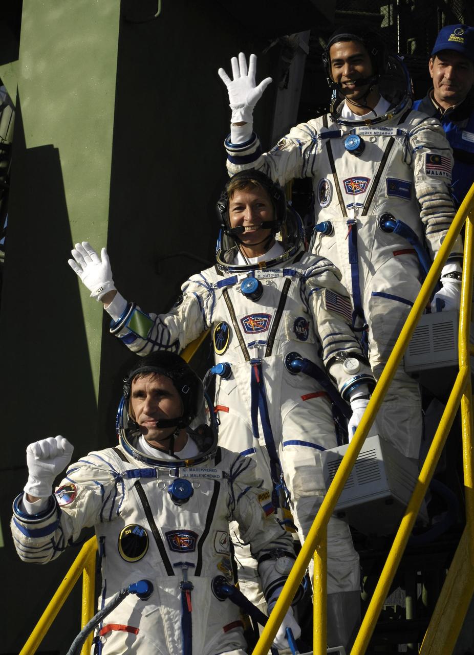 Baikonur, Kazakhstan -- Expedition 16 Commander Peggy Whitson (middle), Flight Engineer and Soyuz Commander Yuri Malenchenko (bottom) and Malaysian Spaceflight Participant Sheikh Muszaphar Shukor wave farewell at the steps of the Soyuz rocket.  The crew launched from the Baikonur Cosmodrome in Kazakhstan at sunset Oct. 10, 2007, in their Soyuz TMA-11 spacecraft bound for a docking to the International Space Station on Oct. 12. Whitson and Malenchenko will spend six months on the station while Shukor will return to Earth Oct. 21 with two of the Expedition 15 crewmembers currently on the complex.  Photo credit: NASA/Bill Ingalls