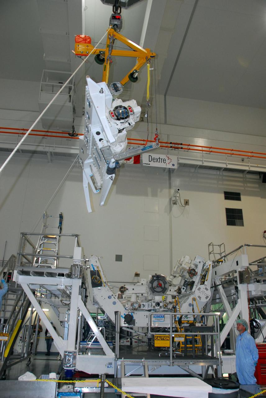KENNEDY SPACE CENTER, FLA. -- In the Space Station Processing Facility at NASA's Kennedy Space Center, the starboard arm of the Special Purpose Dexterous Manipulator, known as Dextre, is moved toward the base, in the background. The arm will be installed on the base. Dextre is a sophisticated dual-armed robot, which is part of Canada's contribution to the International Space Station (ISS). Along with Canadarm2, whose technical name is the Space Station Remote Manipulator System, and a moveable work platform called the Mobile Base System, these three elements form a robotic system called the Mobile Servicing System, or MSS. The three components have been designed to work together or independently. Dextre is part of the payload scheduled on mission STS-123, targeted to launch Feb. 14. Photo credit: NASA/George Shelton