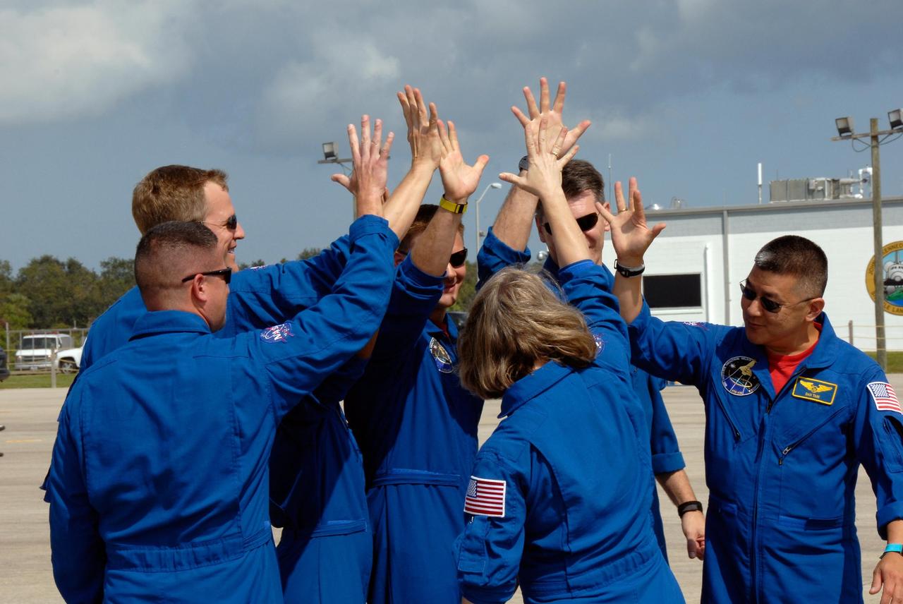 KENNEDY SPACE CENTER, FLA. -- After their arrival at the Shuttle Landing Facility of NASA's Kennedy Space Center, the STS-120 crew shares high-fives for the start of the final leg of their preparation for launch. From left are Pilot George Zamka, Mission Specialists Scott Parazynski and Doug Wheelock, Commander Pamela Melroy (back to camera), and Mission Specialists Paolo Nespoli and Daniel Tani. Not pictured is Mission Specialist Stephanie Wilson. Nespoli represents the European Space Agency. Tani will be remaining on the International Space Station to join the Expedition 16 crew after the mission is complete. The crew has returned to Kennedy to prepare for launch aboard space shuttle Discovery at 11:38 a.m. EDT on Oct. 23. The mission will be the 23rd shuttle flight to the International Space Station, delivering the Italian-built U.S. Node 2, called Harmony. The 14-day mission includes five spacewalks -- four by shuttle crew members and one by the station’s Expedition 16 crew -- to install Harmony and move the P6 solar arrays to their permanent position and deploy them. Discovery is expected to complete its mission and return home at 4:47 a.m. EST on Nov. 6. Photo credit: NASA/Kim Shiflett