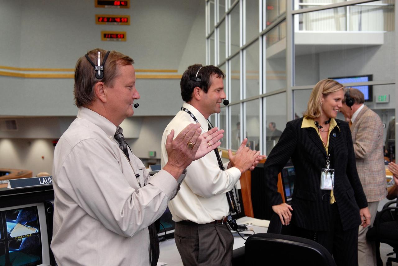 KENNEDY SPACE CENTER, FLA. --  In the firing room of the Launch Control Center at NASA's Kennedy Space Center, Shuttle Launch Director Mike Leinbach and Assistant Launch Director Doug Lyons applaud the mission team for the successful launch of space shuttle Discovery on mission STS-120.  AT right is NASA Flow Director Stephanie Stilson.  Liftoff was on time at 11:38:19 a.m. EDT.  Discovery carries the Italian-built U.S. Node 2, called Harmony.  During the 14-day STS-120 mission, the crew will install Harmony and move the P6 solar arrays to their permanent position and deploy them. Discovery is expected to complete its mission and return home at 4:47 a.m. EST on Nov. 6. Photo credit: NASA/Kim Shiflett