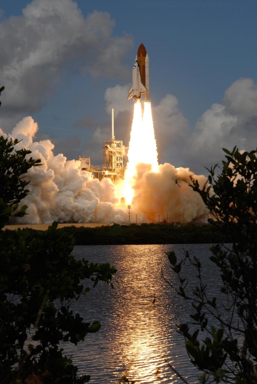 KENNEDY SPACE CENTER, FLA. --  Nearby water reflects the brilliant light of flames beneath space shuttle Discovery as it leaps through the clouds into a blue sky heading for the International Space Station on mission STS-120.   Billows of clouds and smoke stream across Launch Pad 39A at NASA's Kennedy Space Center.   Liftoff was on time at 11:38:19 a.m. EDT.   Discovery carries the Italian-built U.S. Node 2, called Harmony.  During the 14-day STS-120 mission, the crew will install Harmony and move the P6 solar arrays to their permanent position and deploy them. Discovery is expected to complete its mission and return home at 4:47 a.m. EST on Nov. 6. Photo credit: NASA/Sandra Joseph, Tony Gray & Robert Murray