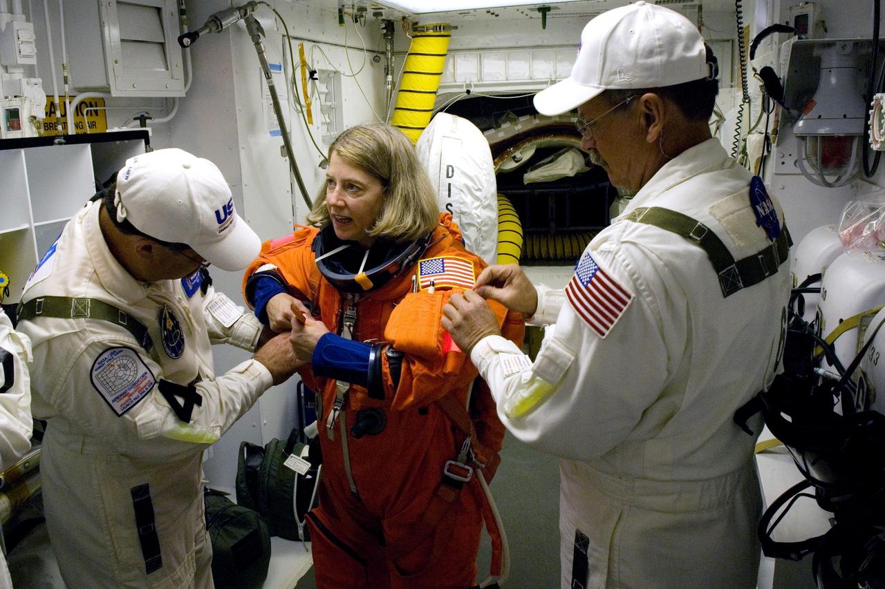 KENNEDY SPACE CENTER, FLA. --  In the White Room on Launch Pad 39A at NASA's Kennedy Space Center, STS-120  Commander Pamela Melroy is helped by the closeout crew to put on a parachute and get ready to enter space shuttle Discovery for liftoff at 11:38 a.m. EDT.  The STS-120 mission will be the 23rd assembly flight to the space station and the 34th flight for Discovery.  Payload on the mission is the Italian-built U.S. Node 2, called Harmony.  During the 14-day mission, the crew will install Harmony and move the P6 solar arrays to their permanent position and deploy them.  Discovery is expected to complete its mission and return home at 4:47 a.m. EST on Nov. 6.   Photo credit: NASA/Scott Haun, Tom Farrar, Rafael Hernandez