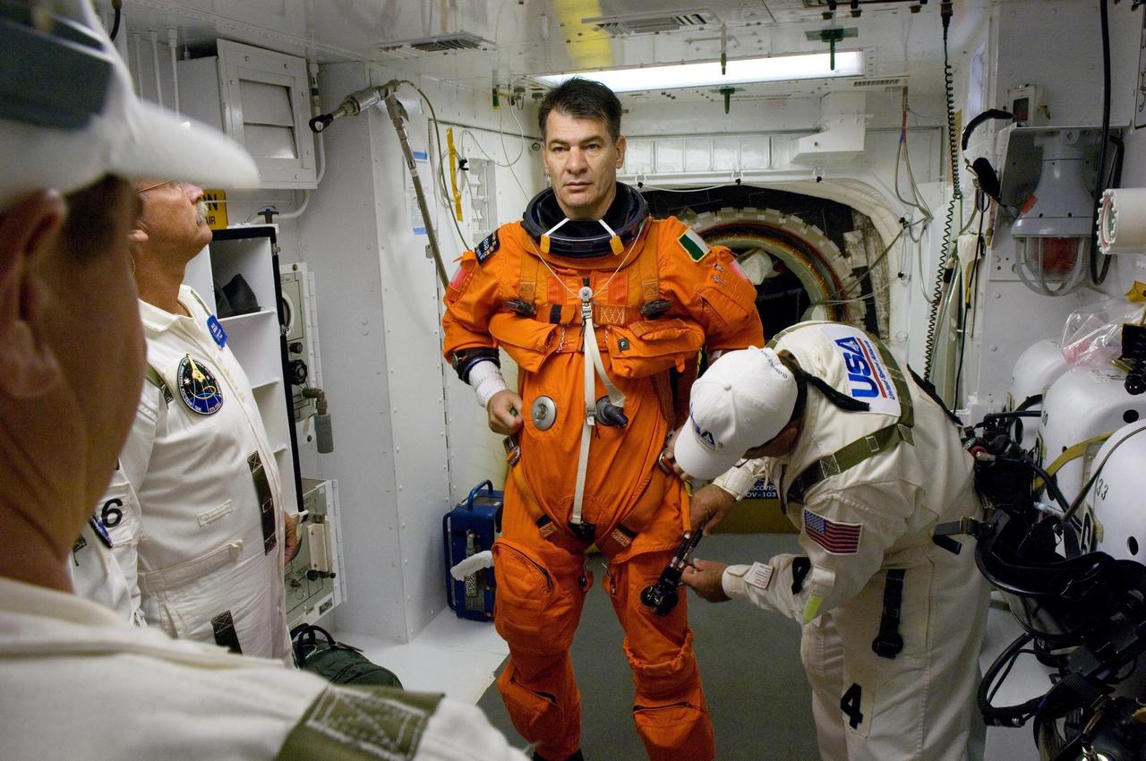KENNEDY SPACE CENTER, FLA. -- In the White Room on Launch Pad 39A at NASA's Kennedy Space Center, STS-120 Mission Specialist Paolo Nespoli is helped by the closeout crew to put on a parachute and get ready to enter space shuttle Discovery for liftoff at 11:38 a.m. EDT.  Nespoli represents the European Space Agency.  The STS-120 mission will be the 23rd assembly flight to the space station and the 34th flight for Discovery.  Payload on the mission is the Italian-built U.S. Node 2, called Harmony.  During the 14-day mission, the crew will install Harmony and move the P6 solar arrays to their permanent position and deploy them.  Discovery is expected to complete its mission and return home at 4:47 a.m. EST on Nov. 6.   Photo credit: NASA/Scott Haun, Tom Farrar, Rafael Hernandez