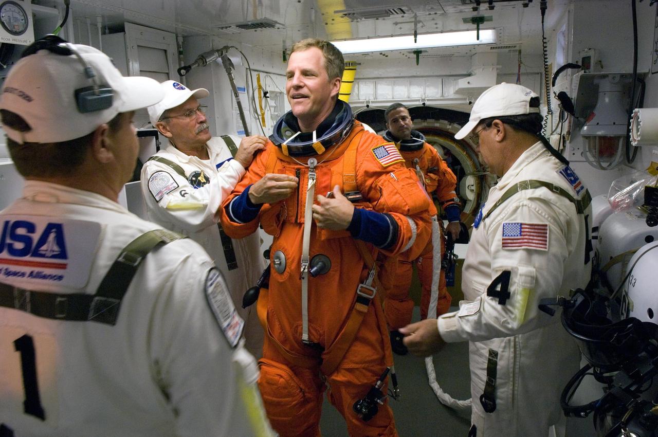KENNEDY SPACE CENTER, FLA. -- In the White Room on Launch Pad 39A at NASA's Kennedy Space Center, STS-120  Mission Specialist Scott Parazynski is helped by the closeout crew to put on a parachute and get ready to enter space shuttle Discovery for liftoff at 11:38 a.m. EDT.  Behind him, near Discovery's hatch opening, is Pilot George Zamka.  The STS-120 mission will be the 23rd assembly flight to the space station and the 34th flight for Discovery.  Payload on the mission is the Italian-built U.S. Node 2, called Harmony.  During the 14-day mission, the crew will install Harmony and move the P6 solar arrays to their permanent position and deploy them.  Discovery is expected to complete its mission and return home at 4:47 a.m. EST on Nov. 6.   Photo credit: NASA/Scott Haun, Tom Farrar, Rafael Hernandez