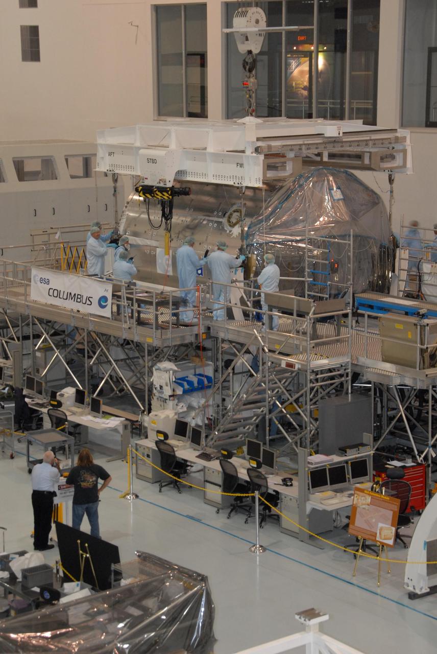 KENNEDY SPACE CENTER, FLA. -- In the Space Station Processing Facility at NASA's Kennedy Space Center, workers attach an overhead crane to the Columbus Laboratory module.  The module will be moved to a weigh station before transfer to the payload canister.  The European Space Agency 's largest single contribution to the International Space Station, Columbus will expand the research facilities of the station, providing crew members and scientists around the world the ability to conduct a variety of life, physical and materials science experiments. The module is approximately 23 feet long and 15 feet wide, allowing it to hold 10 large racks of experiments. The module is scheduled to be transferred to Launch Pad 39A in early November, in preparation for its journey to the station. Columbus will fly aboard space shuttle Atlantis on the STS-122 mission, targeted for launch Dec. 6.  Photo credit: NASA/George Shelton