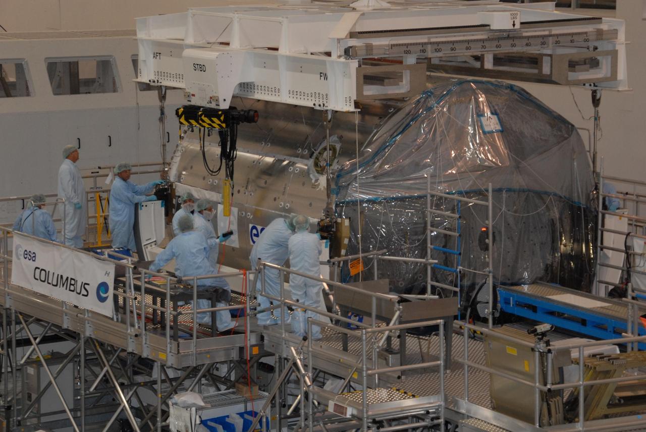 KENNEDY SPACE CENTER, FLA. -- In the Space Station Processing Facility at NASA's Kennedy Space Center, workers attach an overhead crane to the Columbus Laboratory module.  The module will be moved to a weigh station before transfer to the payload canister.  The European Space Agency 's largest single contribution to the International Space Station, Columbus will expand the research facilities of the station, providing crew members and scientists around the world the ability to conduct a variety of life, physical and materials science experiments. The module is approximately 23 feet long and 15 feet wide, allowing it to hold 10 large racks of experiments. The module is scheduled to be transferred to Launch Pad 39A in early November, in preparation for its journey to the station. Columbus will fly aboard space shuttle Atlantis on the STS-122 mission, targeted for launch Dec. 6.  Photo credit: NASA/George Shelton