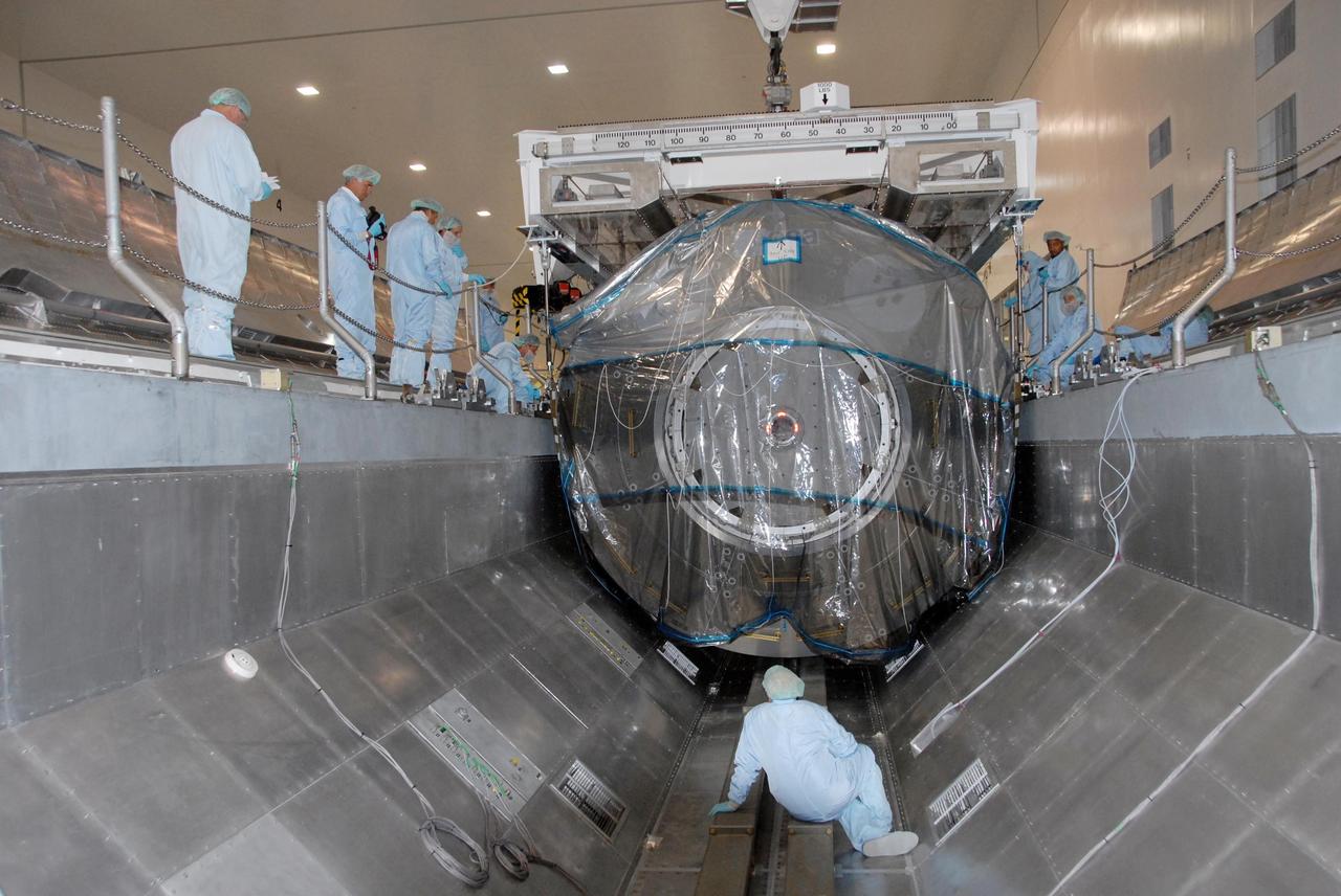 KENNEDY SPACE CENTER, FLA. -- In the Space Station Processing Facility at NASA's Kennedy Space Center, technicians inside and around the payload canister monitor movement of the Columbus Laboratory module as it is lowered into the canister.  The canister will transport the module and other payloads to Launch Pad 39A in preparation for its journey to the International Space Station. The European Space Agency 's largest single contribution to the International Space Station, Columbus will expand the research facilities of the station, providing crew members and scientists around the world the ability to conduct a variety of life, physical and materials science experiments. The module is approximately 23 feet long and 15 feet wide, allowing it to hold 10 large racks of experiments. The module is scheduled to be transferred to Launch Pad 39A in early November, in preparation for its journey to the station. Columbus will fly aboard space shuttle Atlantis on the STS-122 mission, targeted for launch Dec. 6.  Photo credit: NASA/George Shelton