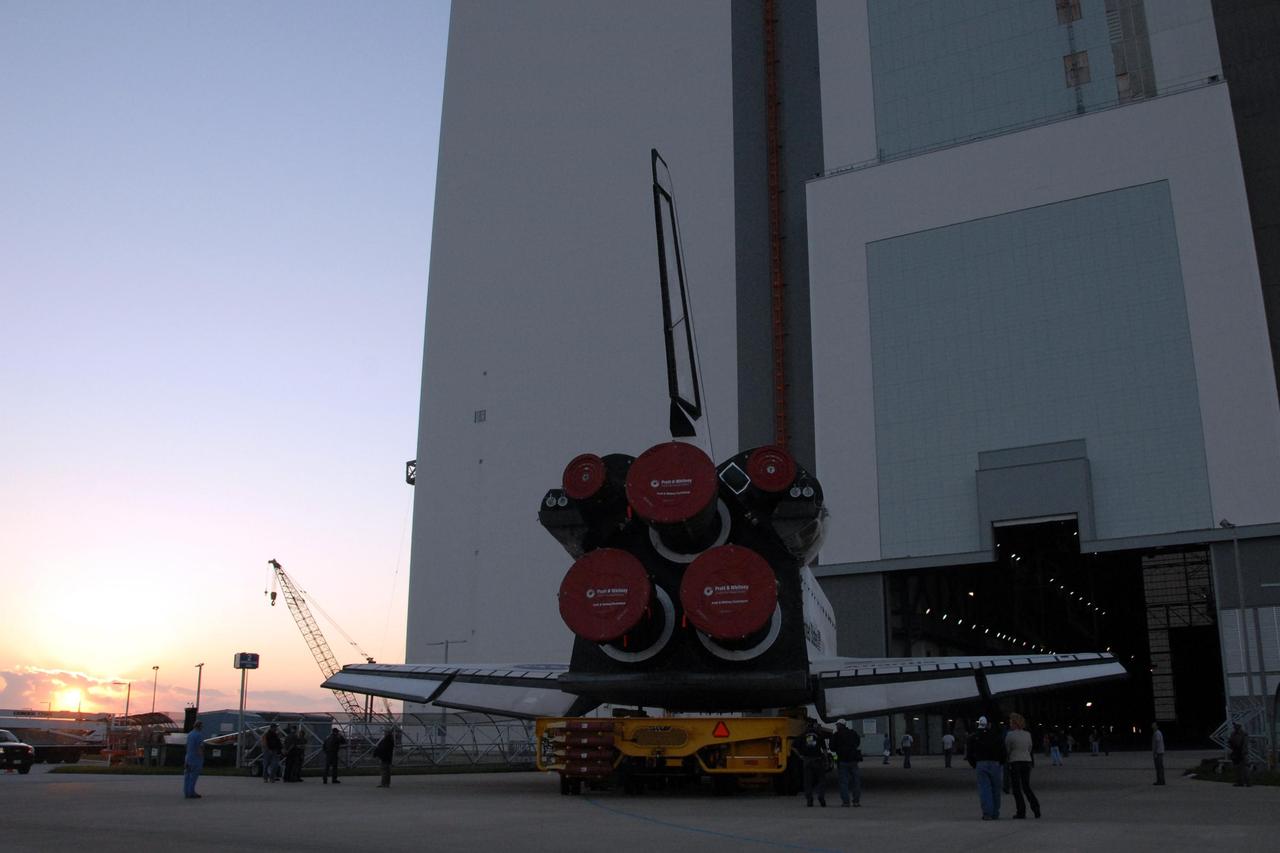 KENNEDY SPACE CENTER, FLA. -- As the sun rises, space shuttle Atlantis turns toward the door of the Vehicle Assembly Building after rolling out of Orbiter Processing Facility bay 1.  Rollover from its processing bay began at 7:05 a.m. EDT. Atlantis arrived in the VAB's transfer aisle at 8:03 a.m. In the VAB, the shuttle will be lifted and mated with the external tank and solid rocket boosters designated for mission STS-122, already secured atop a mobile launcher platform.  On this mission, Atlantis will deliver the Columbus module to the International Space Station.  The European Space Agency's largest contribution to the station, Columbus is a multifunctional, pressurized laboratory that will be permanently attached to U.S. Node 2, called Harmony. The module is approximately 23 feet long and 15 feet wide, allowing it to hold 10 large racks of experiments.  The laboratory will expand the research facilities aboard the station, providing crew members and scientists from around the world the ability to conduct a variety of experiments in the physical, materials and life sciences.  Mission STS-122 is targeted for launch on Dec. 6.  Photo credit: NASA/George Shelton