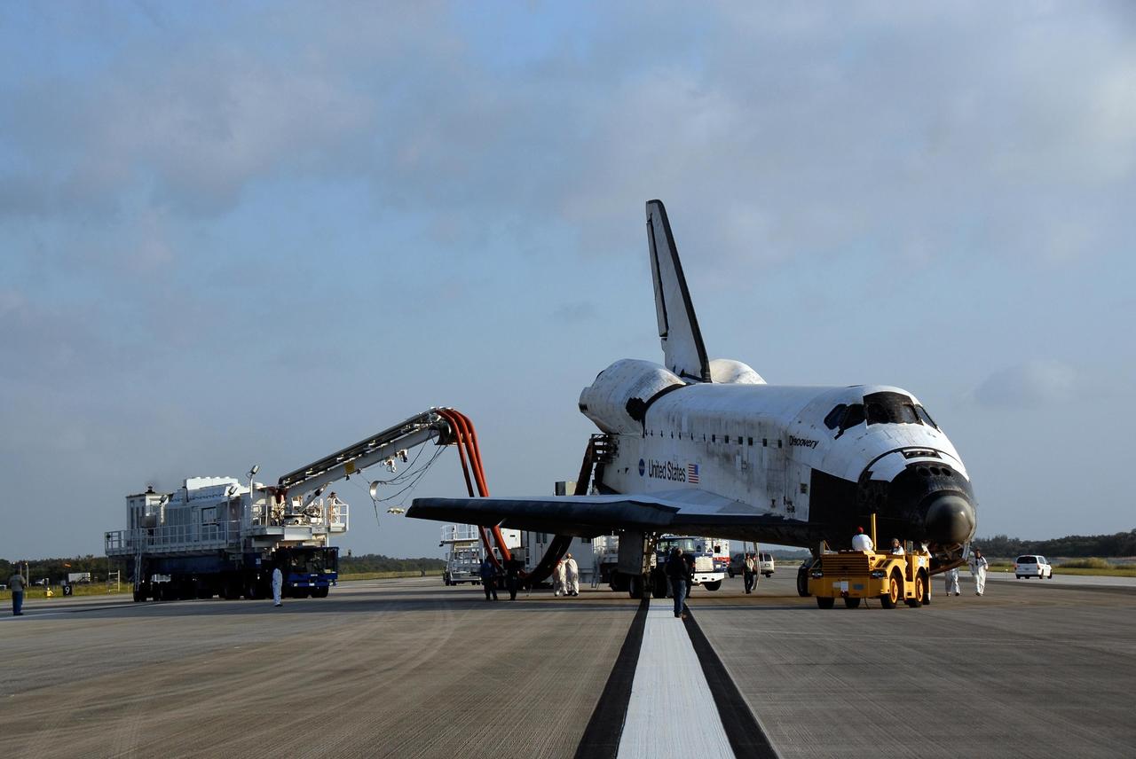 KENNEDY SPACE CENTER, FLA. -- On the Shuttle Landing Facility at NASA's Kennedy Space Center, space shuttle Discovery is ready for towing to the Orbiter Processing Facility, or OPF. Towing normally begins approximately within four hours after landing and is completed within six hours unless removal of time-sensitive experiments require an additional period on the runway. Umbilicals are attached to purge the vehicle of any possible residual explosive or toxic fumes. The tractor tow vehicle will pull Discovery along a two-mile tow-way to the OPF, where processing Discovery for another flight begins. The tow vehicle is very much like the typical towing units used for large aircraft, but it is equipped with a special towing bar designed specifically for the orbiter. In the OPF, turnaround processing procedures on Discovery will include various post-flight deservicing and maintenance functions, which are carried out in parallel with payload removal and the installation of equipment needed for the next mission. Before post-flight deservicing can continue beyond initial safing operations, certain vehicle systems must be mechanically secured and access platforms installed. Discovery completed mission STS-120 with an on-time landing at 1:01 p.m. EST. Photo credit: NASA/Kim Shiflett