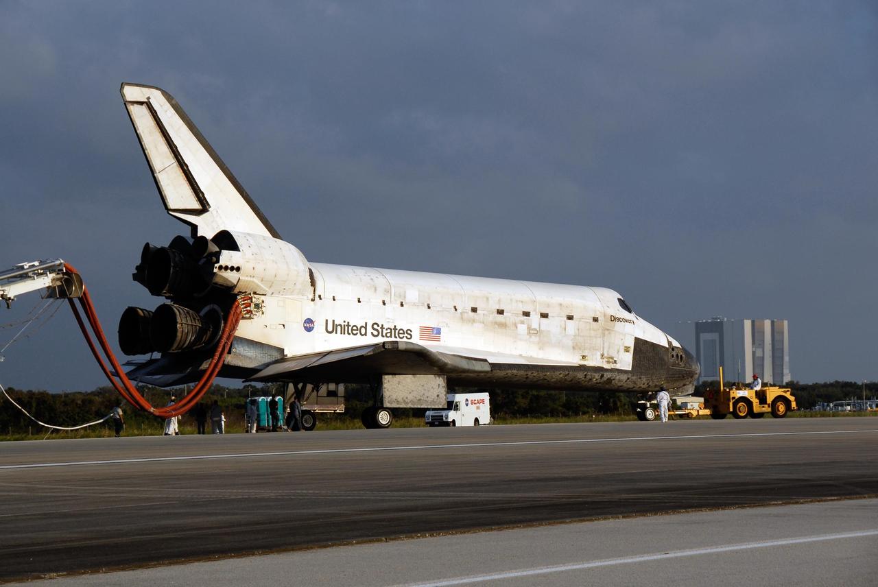 KENNEDY SPACE CENTER, FLA. -- On the Shuttle Landing Facility at NASA's Kennedy Space Center, space shuttle Discovery is towed to the Orbiter Processing Facility, or OPF. Towing normally begins approximately within four hours after landing and is completed within six hours unless removal of time-sensitive experiments requires an additional period on the runway. Umbilicals are attached to purge the vehicle of any possible residual explosive or toxic fumes. The tractor tow vehicle will pull Discovery along a two-mile tow-way to the OPF, where processing Discovery for another flight begins. The tow vehicle is very much like the typical towing units used for large aircraft, but it is equipped with a special towing bar designed specifically for the orbiter. In the OPF, turnaround processing procedures on Discovery will include various post-flight deservicing and maintenance functions, which are carried out in parallel with payload removal and the installation of equipment needed for the next mission. Before post-flight deservicing can continue beyond initial safing operations, certain vehicle systems must be mechanically secured and access platforms installed. Discovery completed mission STS-120 with an on-time landing at 1:01 p.m. EST. Photo credit: NASA/Kim Shiflett