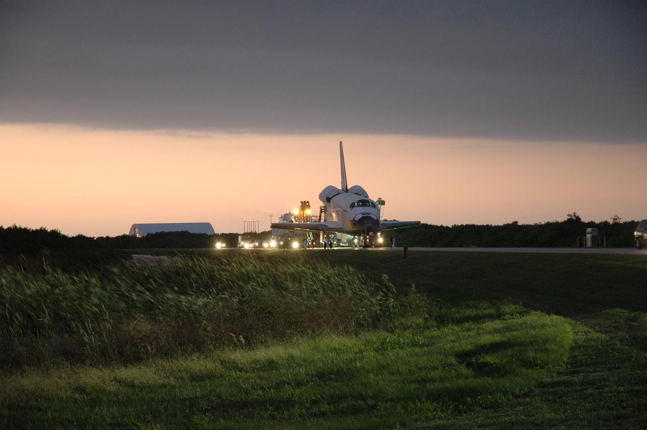 KENNEDY SPACE CENTER, FLA. --  In the waning light, space shuttle Discovery is towed along a two-mile tow-way to the Orbital Processing Facility, or OPF, where processing Discovery for another flight begins.  Towing normally begins within four hours after landing and is completed within six hours unless removal of time-sensitive experiments is required on the runway.   In the OPF, turnaround processing procedures on Discovery will include various post-flight deservicing and maintenance functions, which are carried out in parallel with payload removal and the installation of equipment needed for the next mission.  Before post-flight deservicing can continue beyond initial safing operations, certain vehicle systems must be mechanically secured and access platforms installed.  Discovery completed mission STS-120 with an on-time landing at 1:01 p.m. EST. Photo credit: NASA/Jim Grossmann
