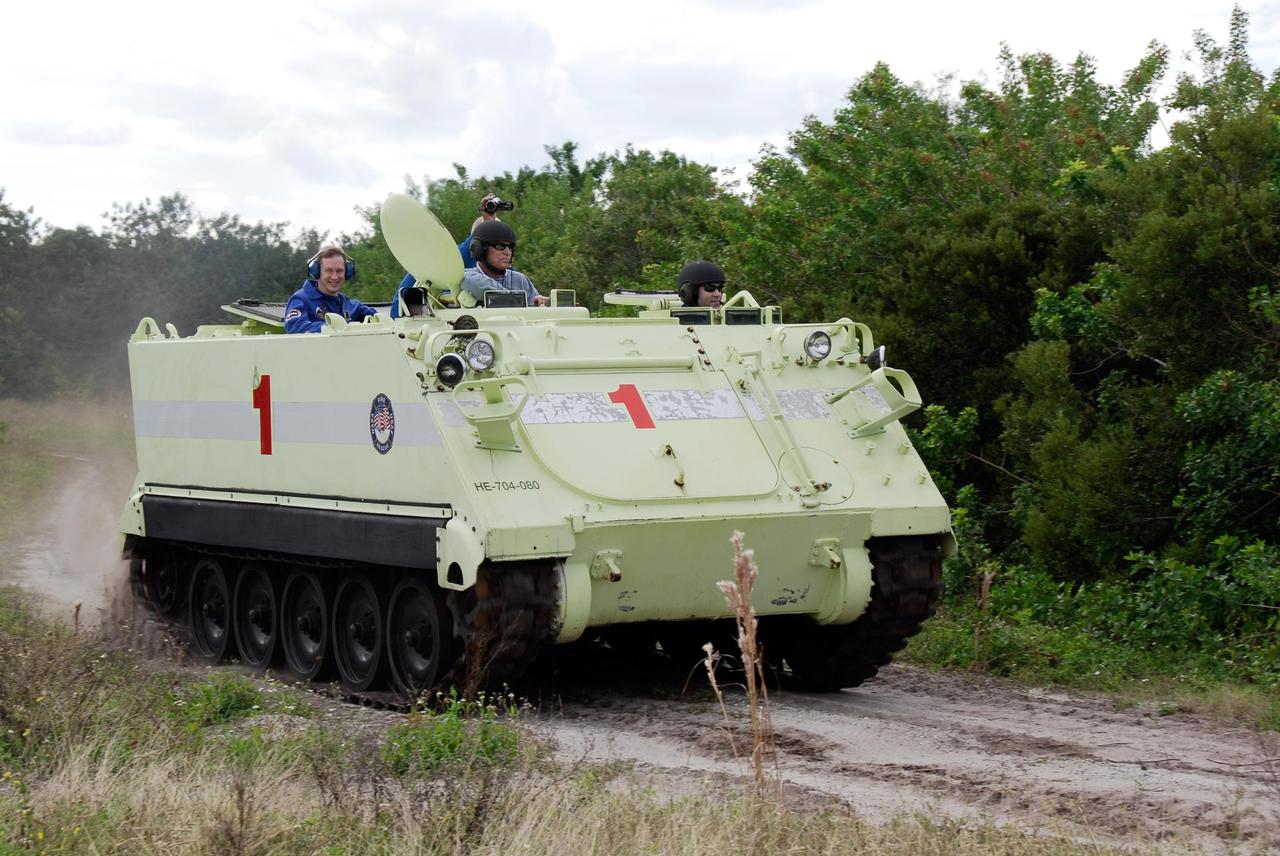 KENNEDY SPACE CENTER, FLA. --  STS-122 Commander Stephen Frick, at right, practices driving an M-113 armored personnel carrier as an instructor, at left, monitors his performance.  European Space Agency astronaut Frank De Winne, the backup for STS-122 Mission Specialist Leopold Eyharts, rides in back.  The practice near Launch Pad 39B is part of training on emergency egress procedures. An M-113 will be available to transport the crew to safety in the event of a contingency on the pad before their launch. The crew is participating in Terminal Countdown Demonstration Test activities, a standard part of launch preparations. The TCDT provides astronauts and ground crews with equipment familiarization, emergency egress training and a simulated launch countdown. On mission STS-122, Atlantis will deliver the European Space Agency's Columbus module to the International Space Station.  Columbus is a multifunctional, pressurized laboratory that will be permanently attached to U.S. Node 2, called Harmony, and will expand the research facilities aboard the station. Launch is targeted for Dec. 6.  Photo credit: NASA/Kim Shiflett
