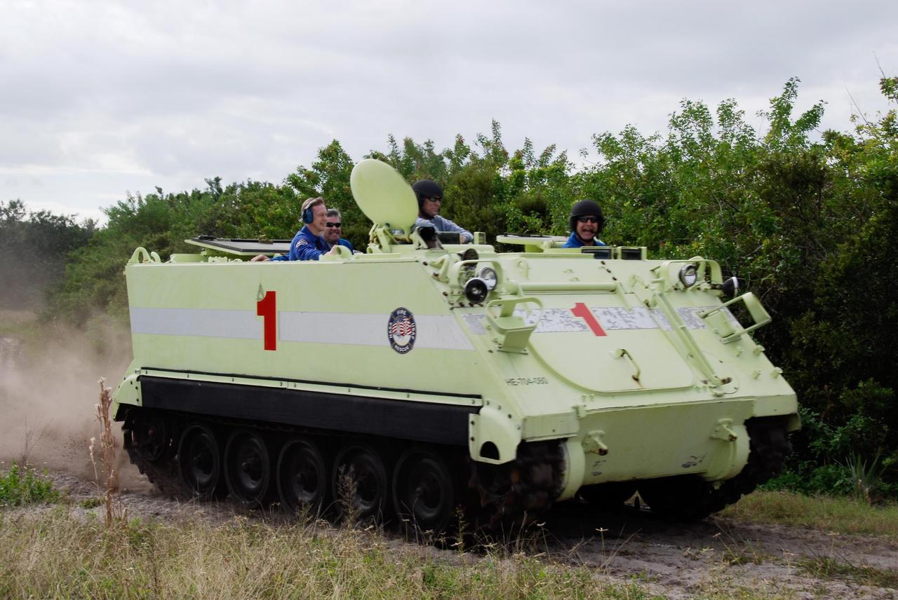 KENNEDY SPACE CENTER, FLA. --  STS-122 Pilot Alan Poindexter, at right, seems to enjoy driving an M-113 armored personnel carrier as the instructor behind him monitors his performance.  European Space Agency astronaut Frank De Winne, at left, the backup for STS-122 Mission Specialist Leopold Eyharts, is along for the ride.  The practice near Launch Pad 39B is part of training on emergency egress procedures. An M-113 will be available to transport the crew to safety in the event of a contingency on the pad before their launch.  The crew is participating in Terminal Countdown Demonstration Test activities, a standard part of launch preparations. The TCDT provides astronauts and ground crews with equipment familiarization, emergency egress training and a simulated launch countdown. On mission STS-122, Atlantis will deliver the European Space Agency's Columbus module to the International Space Station.  Columbus is a multifunctional, pressurized laboratory that will be permanently attached to U.S. Node 2, called Harmony, and will expand the research facilities aboard the station. Launch is targeted for Dec. 6.  Photo credit: NASA/Kim Shiflett