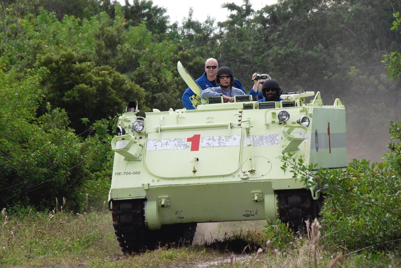 KENNEDY SPACE CENTER, FLA. --  STS-122 Mission Specialist Leland Melvin, at right, practices driving an M-113 armored personnel carrier as the instructor beside him monitors his performance.  STS-122 Pilot Alan Poindexter, at left, rides in back.  The practice near Launch Pad 39B is part of training on emergency egress procedures. An M-113 will be available to transport the crew to safety in the event of a contingency on the pad before their launch.  The crew is participating in Terminal Countdown Demonstration Test activities, a standard part of launch preparations. The TCDT provides astronauts and ground crews with equipment familiarization, emergency egress training and a simulated launch countdown. On mission STS-122, Atlantis will deliver the European Space Agency's Columbus module to the International Space Station.  Columbus is a multifunctional, pressurized laboratory that will be permanently attached to U.S. Node 2, called Harmony, and will expand the research facilities aboard the station. Launch is targeted for Dec. 6.  Photo credit: NASA/Kim Shiflett