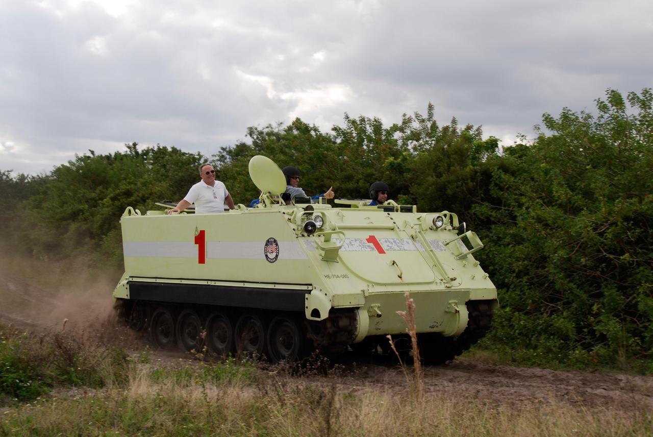 KENNEDY SPACE CENTER, FLA. --  STS-122 Mission Specialist Stanley Love, at right, practices driving an M-113 armored personnel carrier as the instructor behind him monitors his performance.  Former astronaut Jerry Ross, chief of the Vehicle Integration Test Office at NASA Johnson Space Center, enjoys the ride in back.  The practice near Launch Pad 39B is part of training on emergency egress procedures. An M-113 will be available to transport the crew to safety in the event of a contingency on the pad before their launch.  The crew is participating in Terminal Countdown Demonstration Test activities, a standard part of launch preparations. The TCDT provides astronauts and ground crews with equipment familiarization, emergency egress training and a simulated launch countdown. On mission STS-122, Atlantis will deliver the European Space Agency's Columbus module to the International Space Station.  Columbus is a multifunctional, pressurized laboratory that will be permanently attached to U.S. Node 2, called Harmony, and will expand the research facilities aboard the station. Launch is targeted for Dec. 6.  Photo credit: NASA/Kim Shiflett